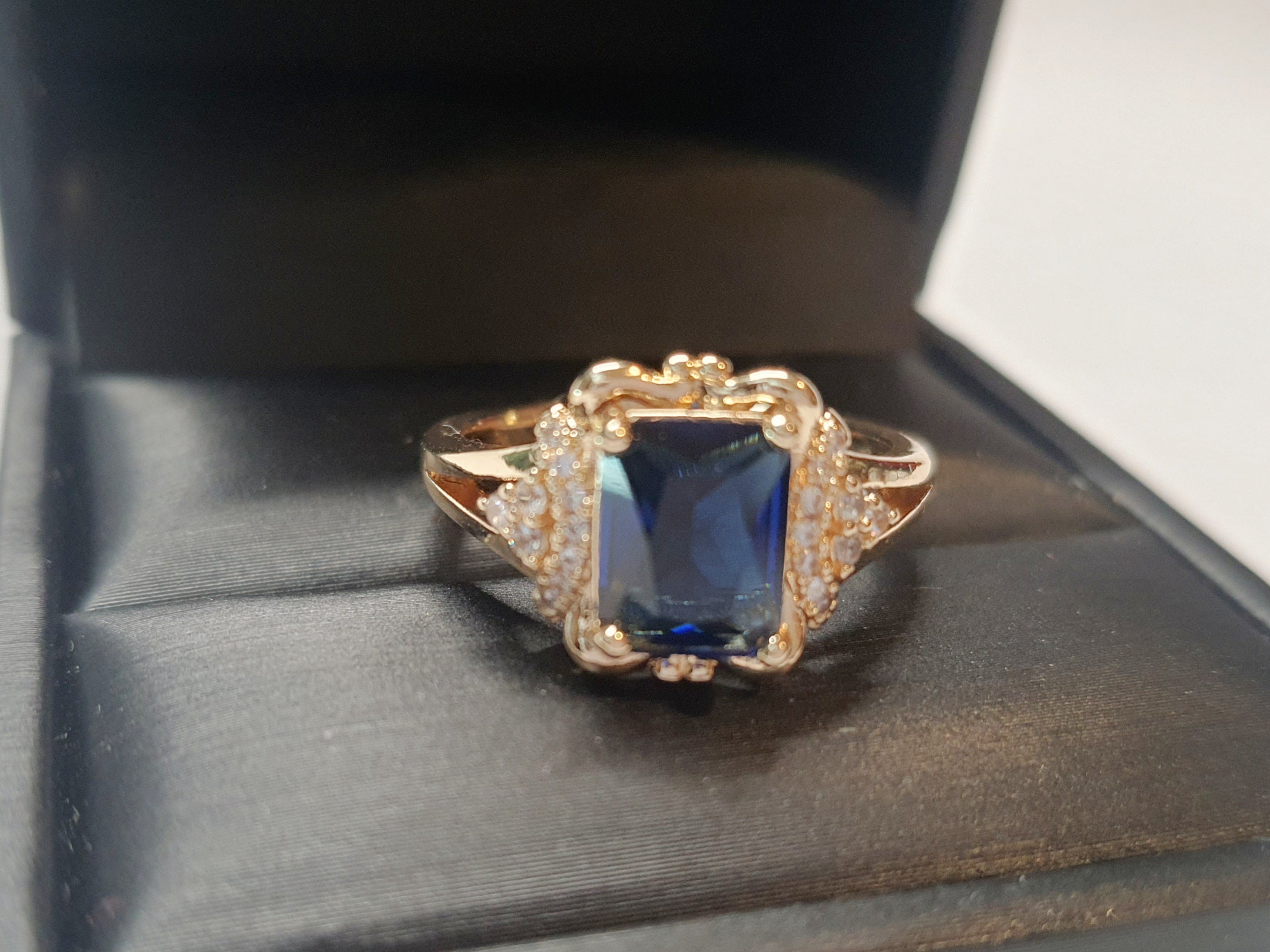 Złoty pierścionek ze stali nierdzewnej z granatowym kamieniem w szlifie szmaragdowym i cyrkoniami po bokach w stylu glamour klasycznym. Rozmiar 20 mm. stal chirurgiczna, stal nierdzewna, wodoodporne, hipoalergiczne, jakość premium, RougeBizu.