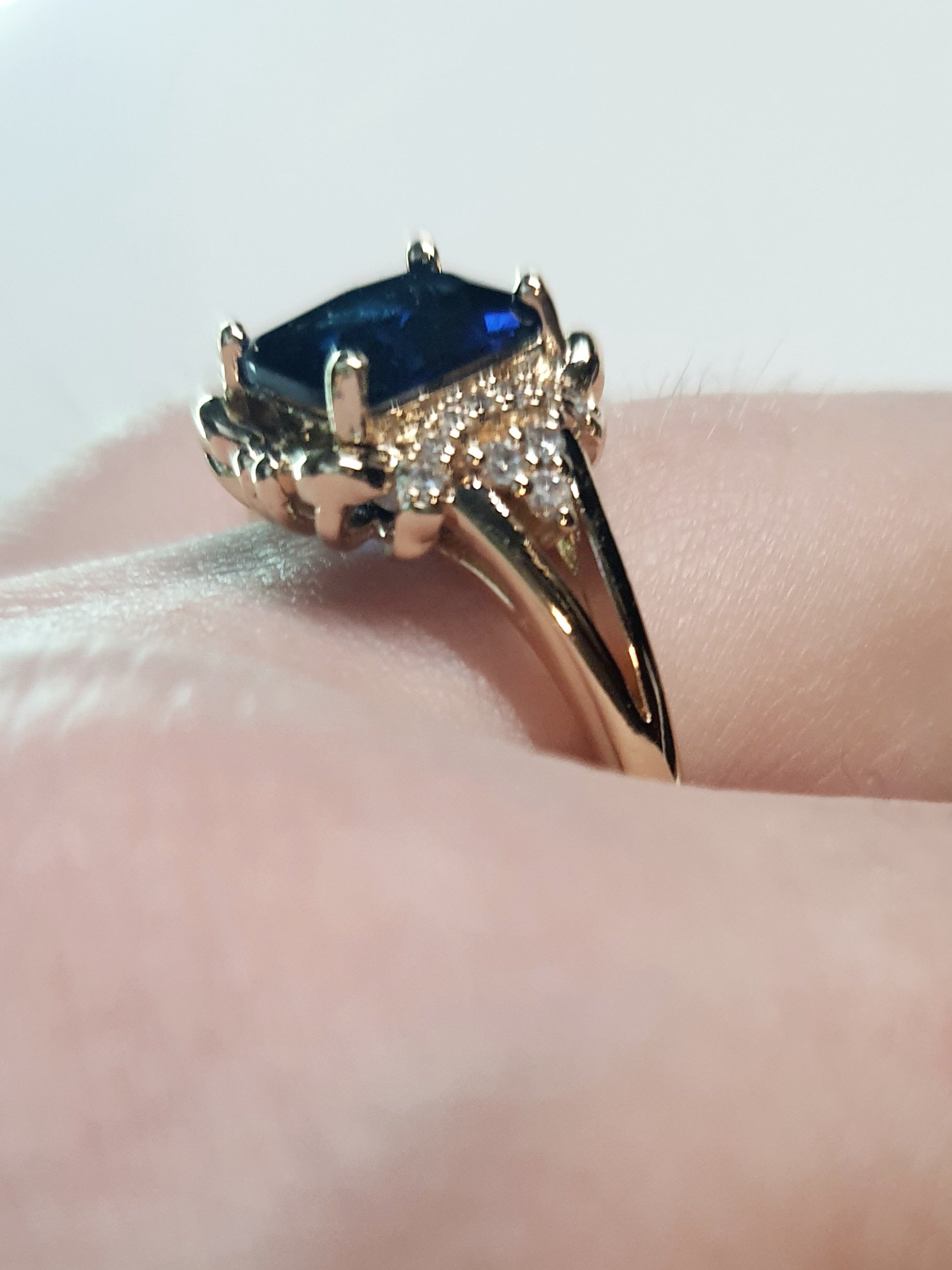 Złoty pierścionek ze stali nierdzewnej z granatowym kamieniem w szlifie szmaragdowym i cyrkoniami po bokach w stylu glamour klasycznym. Rozmiar 20 mm. stal chirurgiczna, stal nierdzewna, wodoodporne, hipoalergiczne, jakość premium, RougeBizu.