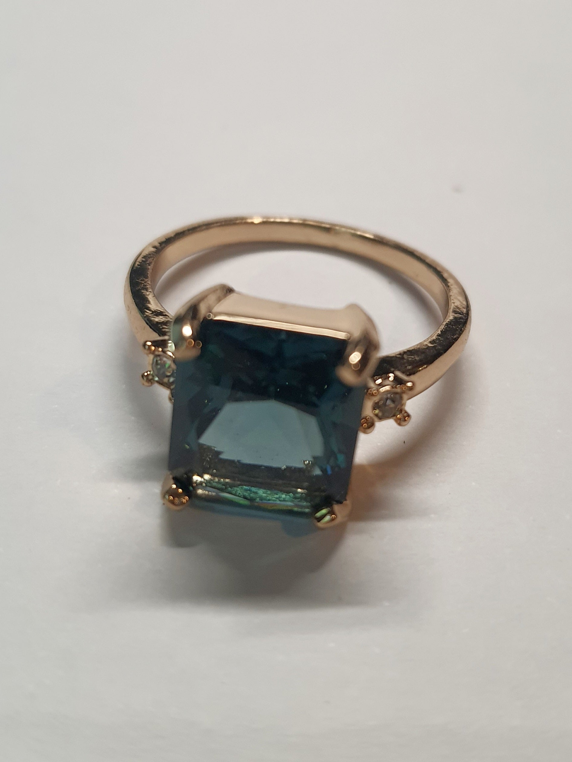 Złoty pierścionek ze stali nierdzewnej z prostokątnym szafirowym kamieniem i drobnymi cyrkoniami po bokach w stylu klasycznym glamour. Rozmiar 19 mm. stal chirurgiczna, stal nierdzewna, wodoodporne, hipoalergiczne, jakość premium, RougeBizu.