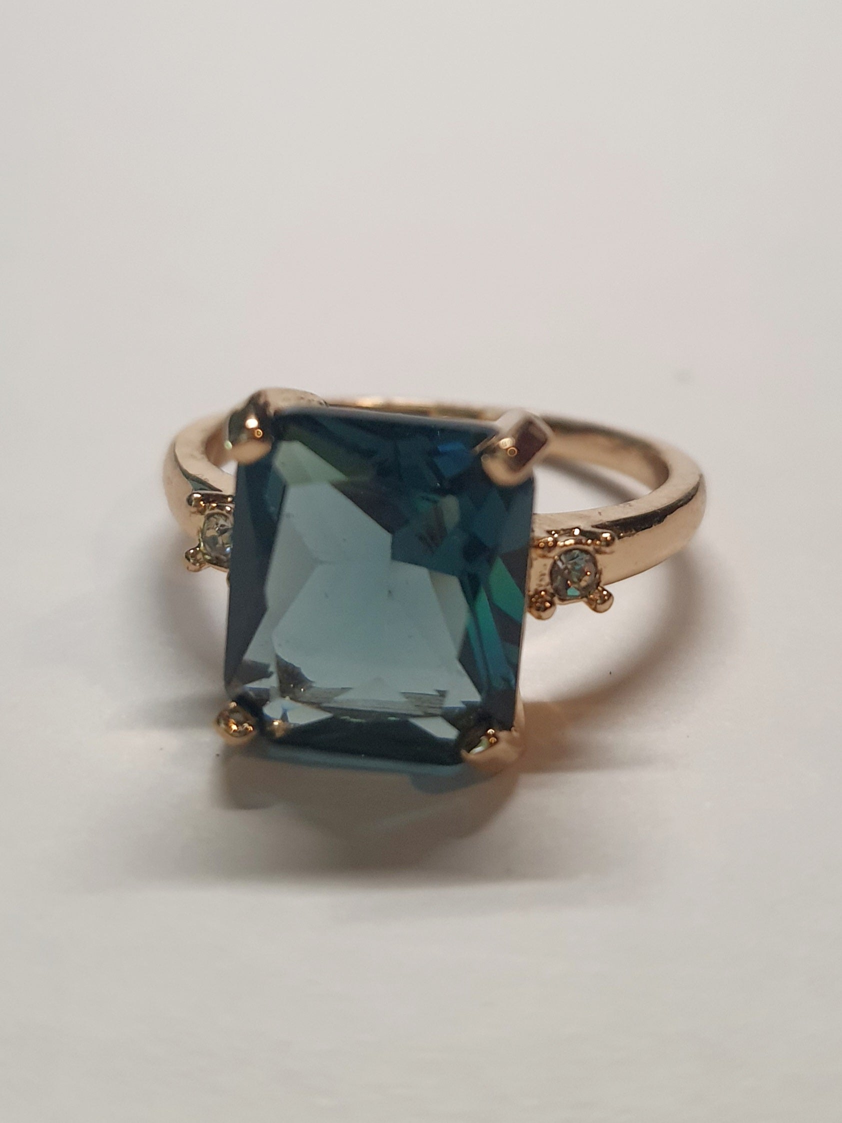Złoty pierścionek ze stali nierdzewnej z prostokątnym szafirowym kamieniem i drobnymi cyrkoniami po bokach w stylu klasycznym glamour. Rozmiar 19 mm. stal chirurgiczna, stal nierdzewna, wodoodporne, hipoalergiczne, jakość premium, RougeBizu.