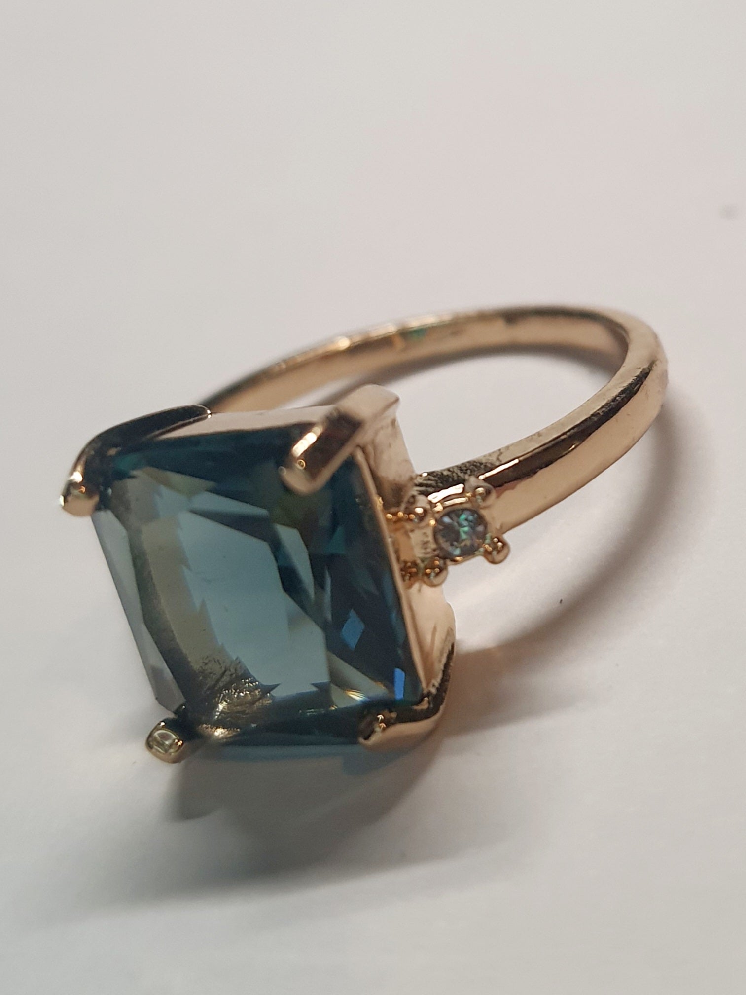 Złoty pierścionek ze stali nierdzewnej z prostokątnym szafirowym kamieniem i drobnymi cyrkoniami po bokach w stylu klasycznym glamour. Rozmiar 19 mm. stal chirurgiczna, stal nierdzewna, wodoodporne, hipoalergiczne, jakość premium, RougeBizu.