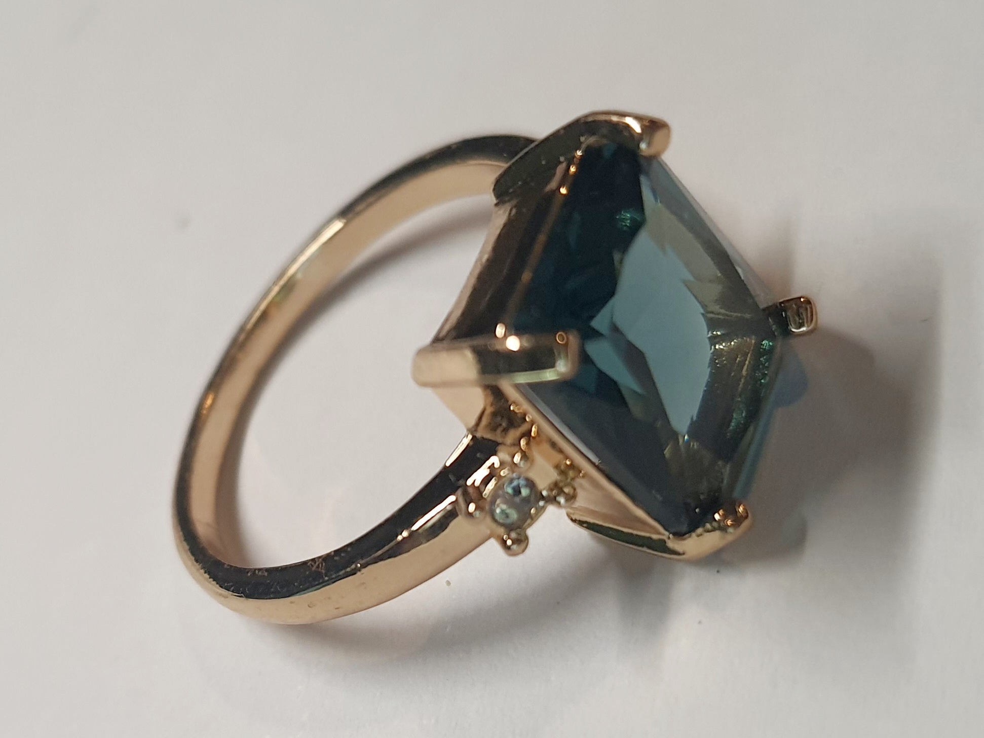 Złoty pierścionek ze stali nierdzewnej z prostokątnym szafirowym kamieniem i drobnymi cyrkoniami po bokach w stylu klasycznym glamour. Rozmiar 19 mm. stal chirurgiczna, stal nierdzewna, wodoodporne, hipoalergiczne, jakość premium, RougeBizu.