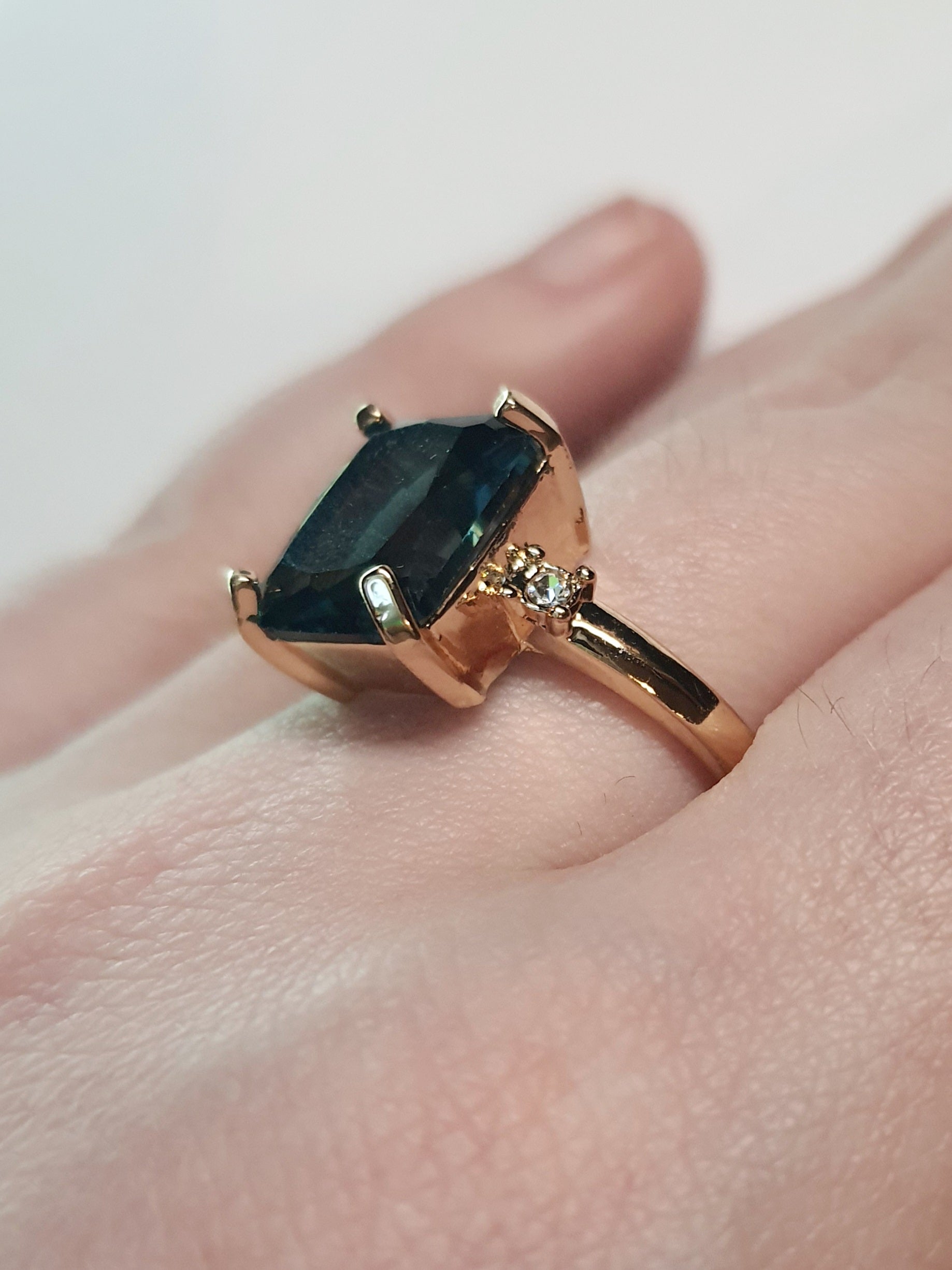 Złoty pierścionek ze stali nierdzewnej z prostokątnym szafirowym kamieniem i drobnymi cyrkoniami po bokach w stylu klasycznym glamour. Rozmiar 19 mm. stal chirurgiczna, stal nierdzewna, wodoodporne, hipoalergiczne, jakość premium, RougeBizu.