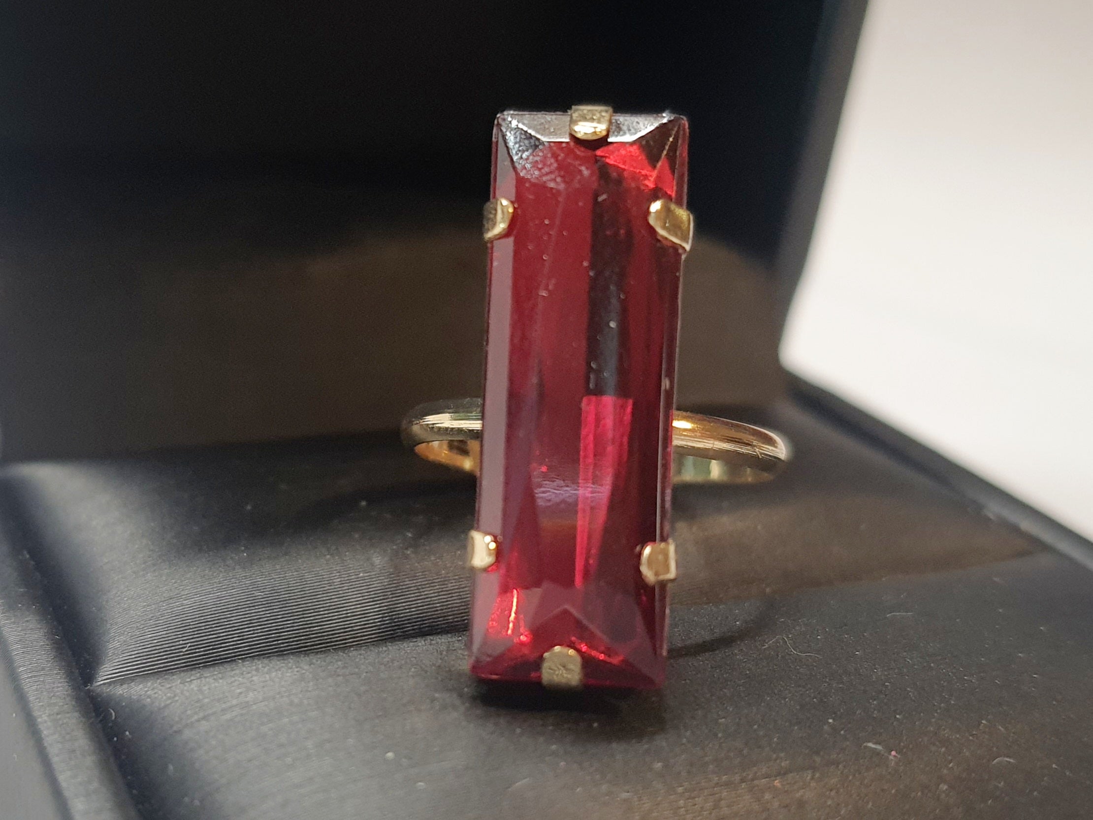 Złoty pierścionek z długim rubinowym kamieniem w stylu glamour, elegancki i efektowny. Rozmiar 17 mm, lekko regulowany. Stal nierdzewna, stal chirurgiczna, wodoodporne, hipoalergiczne, jakość premium. Rouge Bizu.