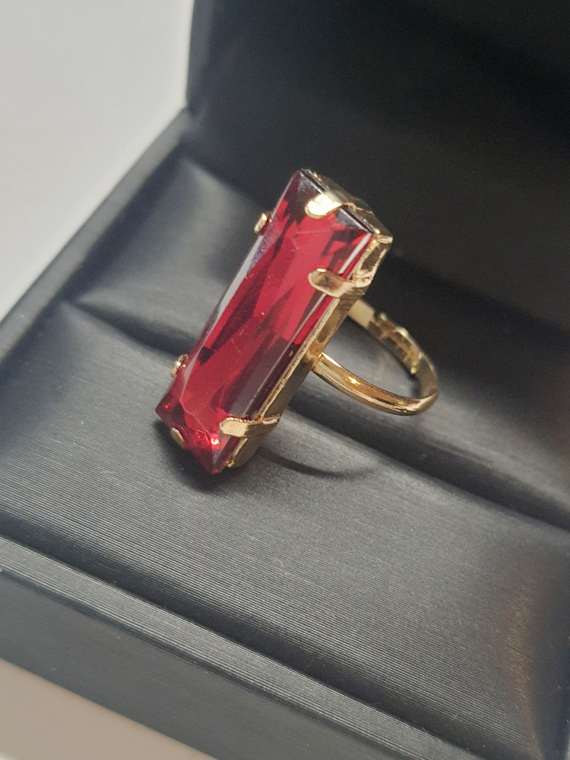 Złoty pierścionek z długim rubinowym kamieniem w stylu glamour, elegancki i efektowny. Rozmiar 17 mm, lekko regulowany. Stal nierdzewna, stal chirurgiczna, wodoodporne, hipoalergiczne, jakość premium. Rouge Bizu.