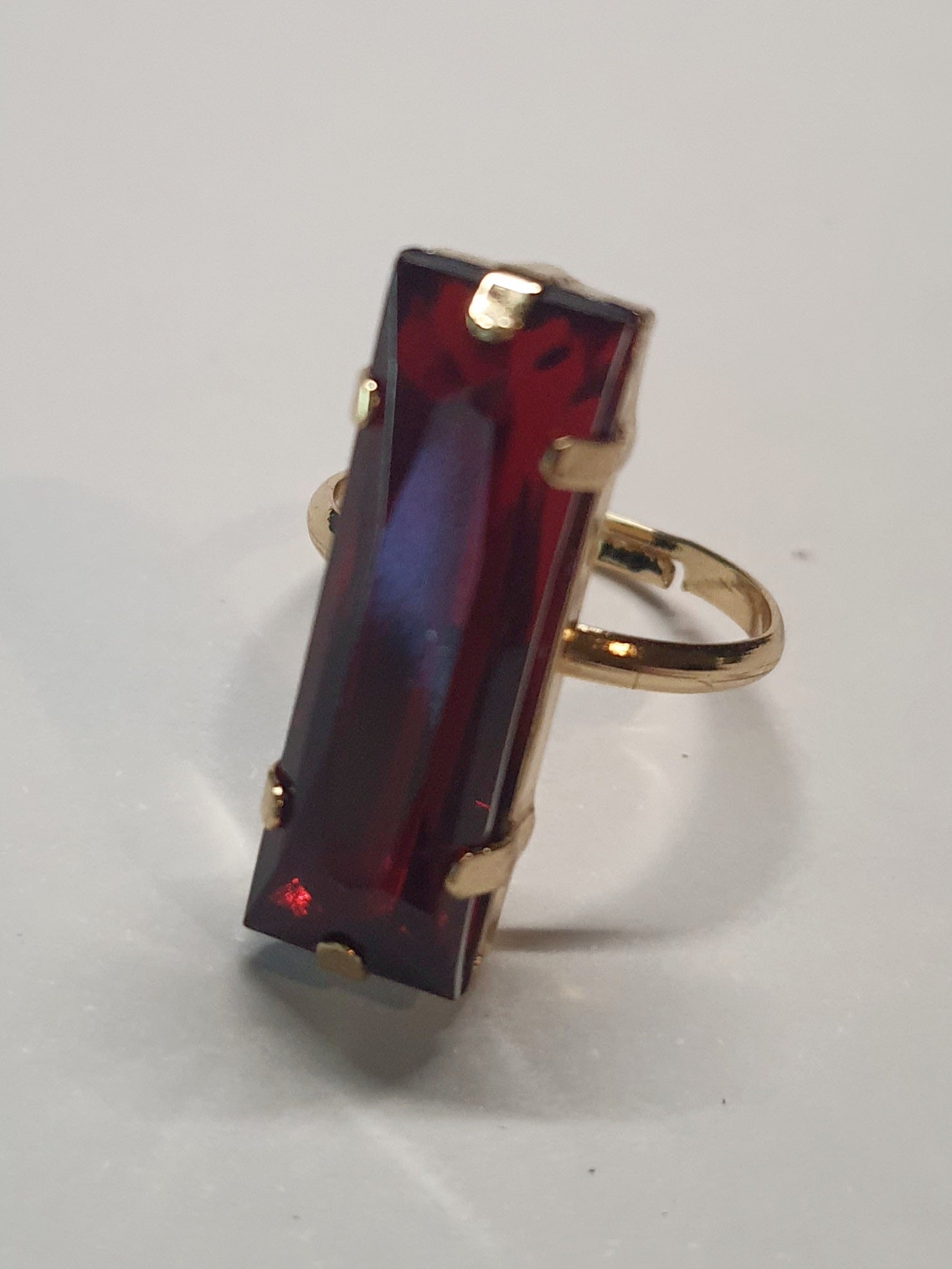 Złoty pierścionek z długim rubinowym kamieniem w stylu glamour, elegancki i efektowny. Rozmiar 17 mm, lekko regulowany. Stal nierdzewna, stal chirurgiczna, wodoodporne, hipoalergiczne, jakość premium. Rouge Bizu.