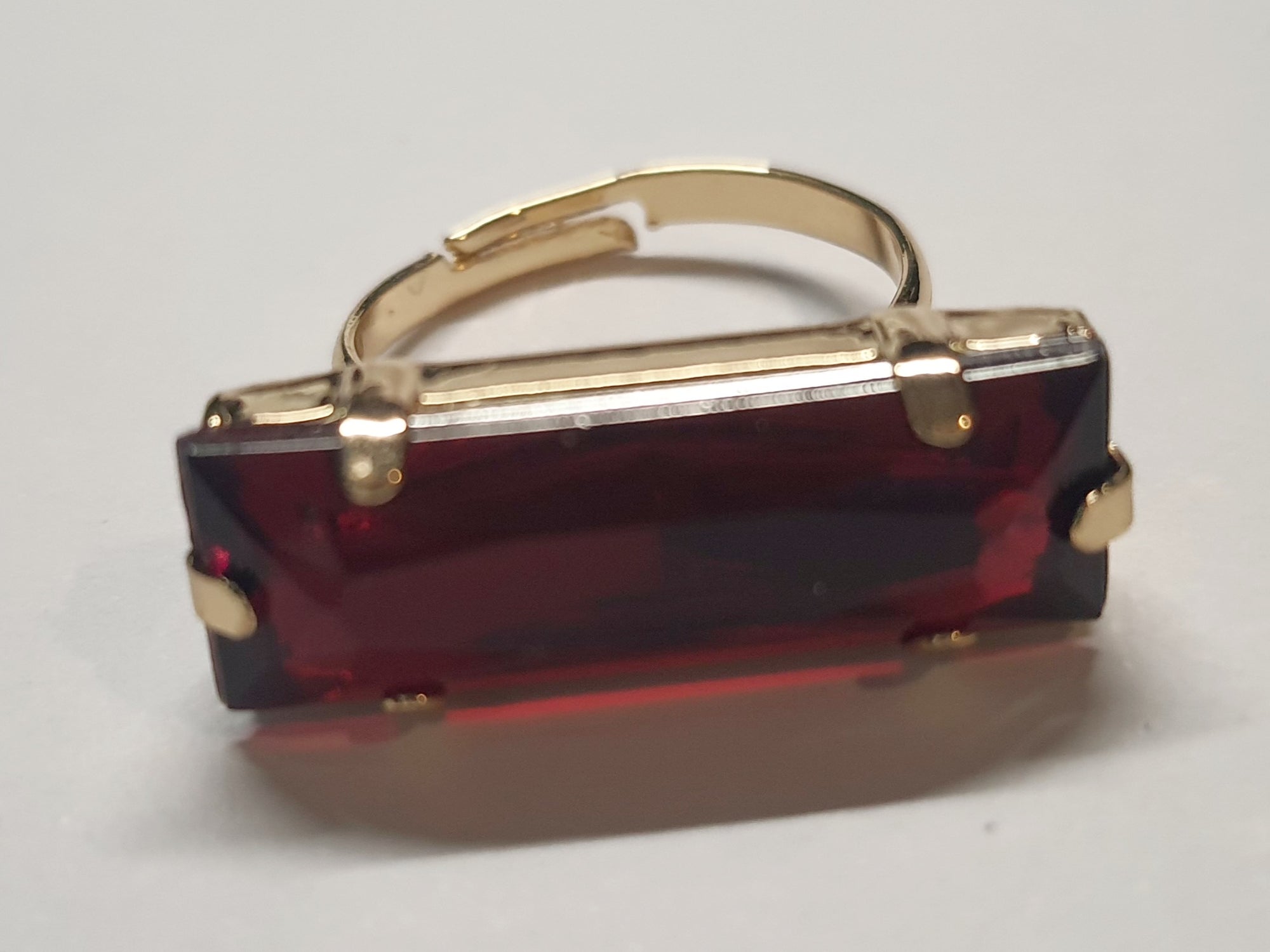 Złoty pierścionek z długim rubinowym kamieniem w stylu glamour vintage, elegancki i efektowny. Rozmiar 17 mm, lekko regulowany. Stal nierdzewna, stal chirurgiczna, wodoodporne, hipoalergiczne, jakość premium. Rouge Bizu.