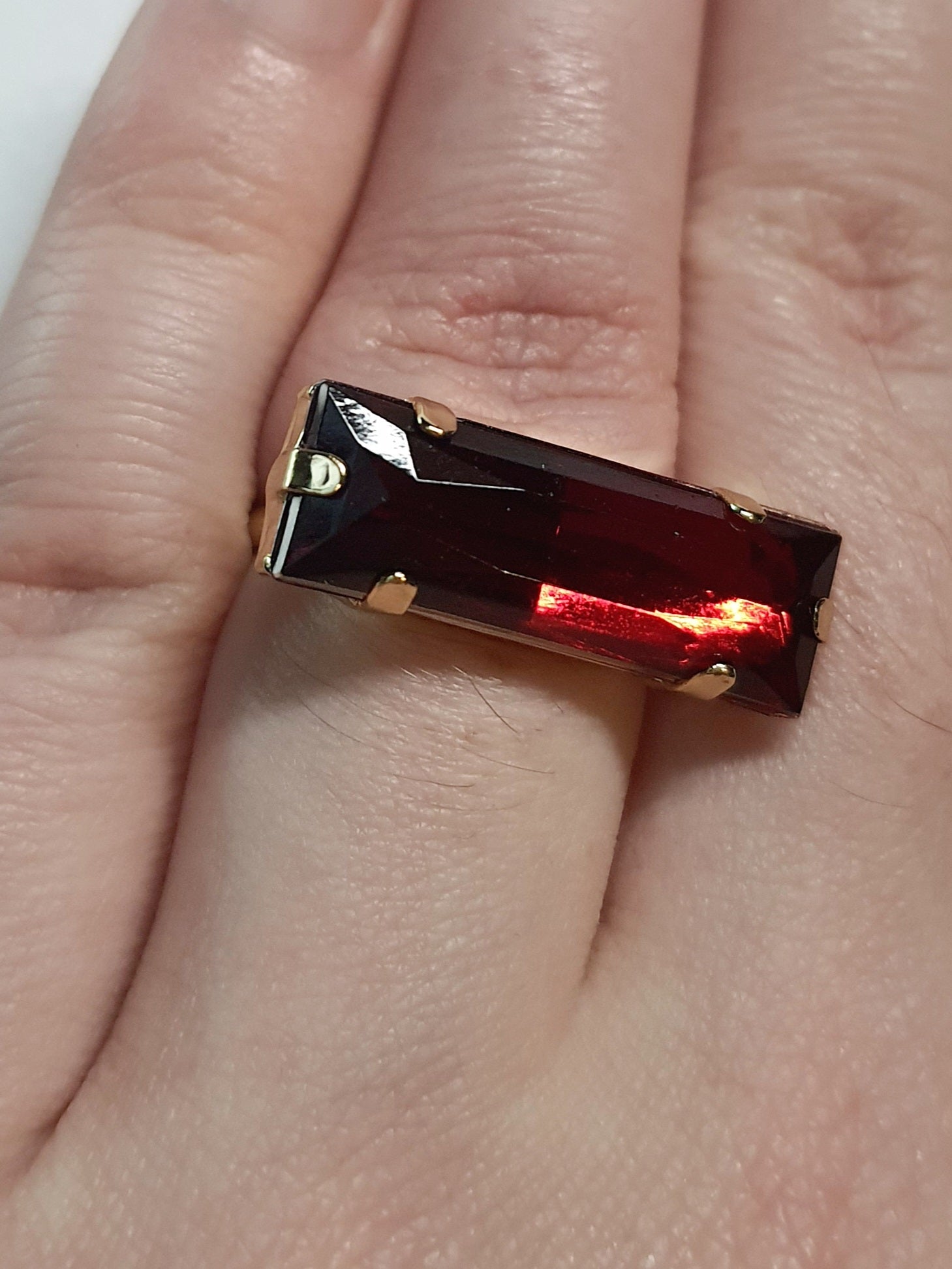 Złoty pierścionek z długim rubinowym kamieniem w stylu glamour vintage, elegancki i efektowny. Rozmiar 17 mm, lekko regulowany. Stal nierdzewna, stal chirurgiczna, wodoodporne, hipoalergiczne, jakość premium. Rouge Bizu.