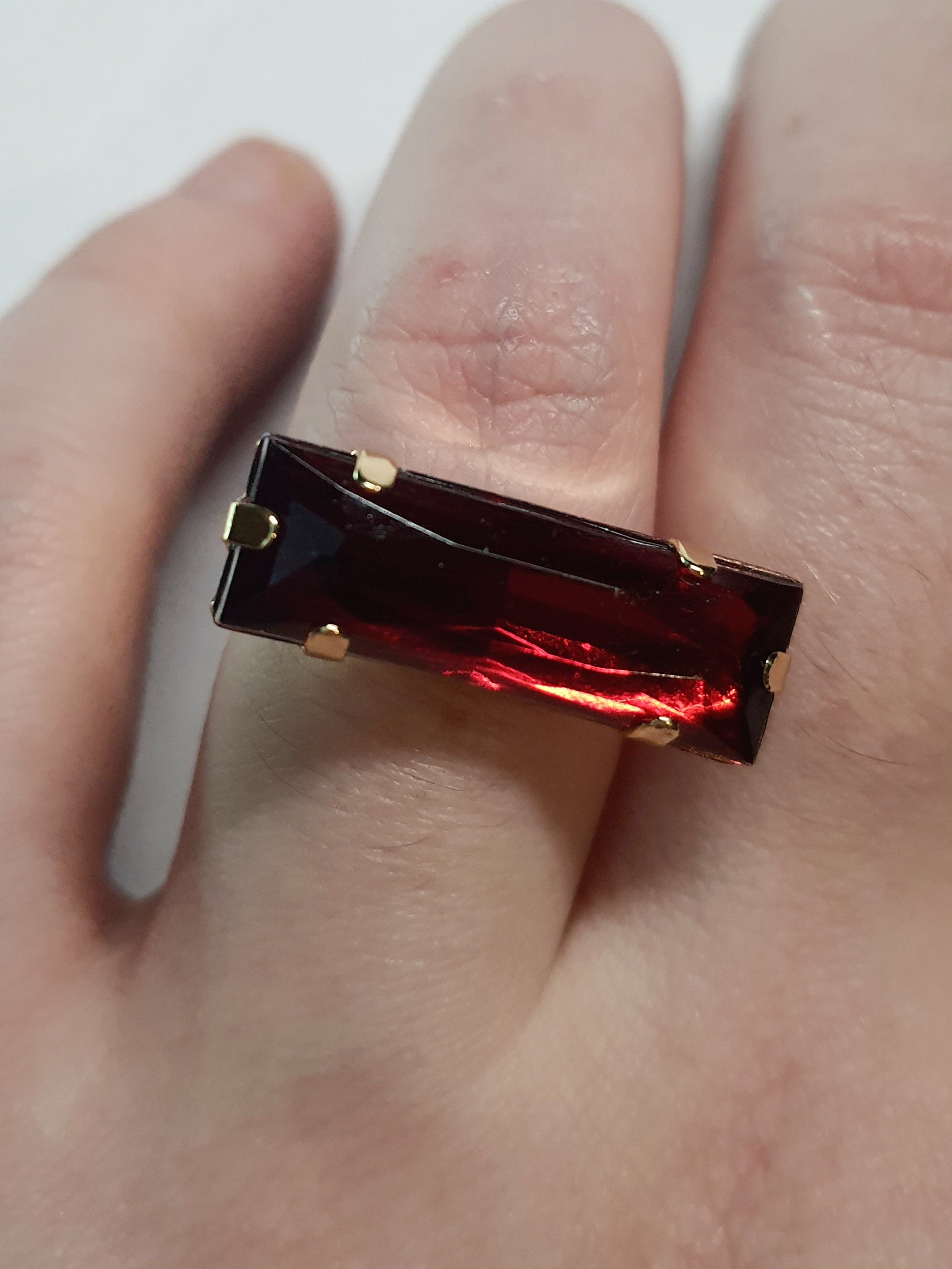 Złoty pierścionek z długim rubinowym kamieniem w stylu glamour vintage, elegancki i efektowny. Rozmiar 17 mm, lekko regulowany. Stal nierdzewna, stal chirurgiczna, wodoodporne, hipoalergiczne, jakość premium. Rouge Bizu.