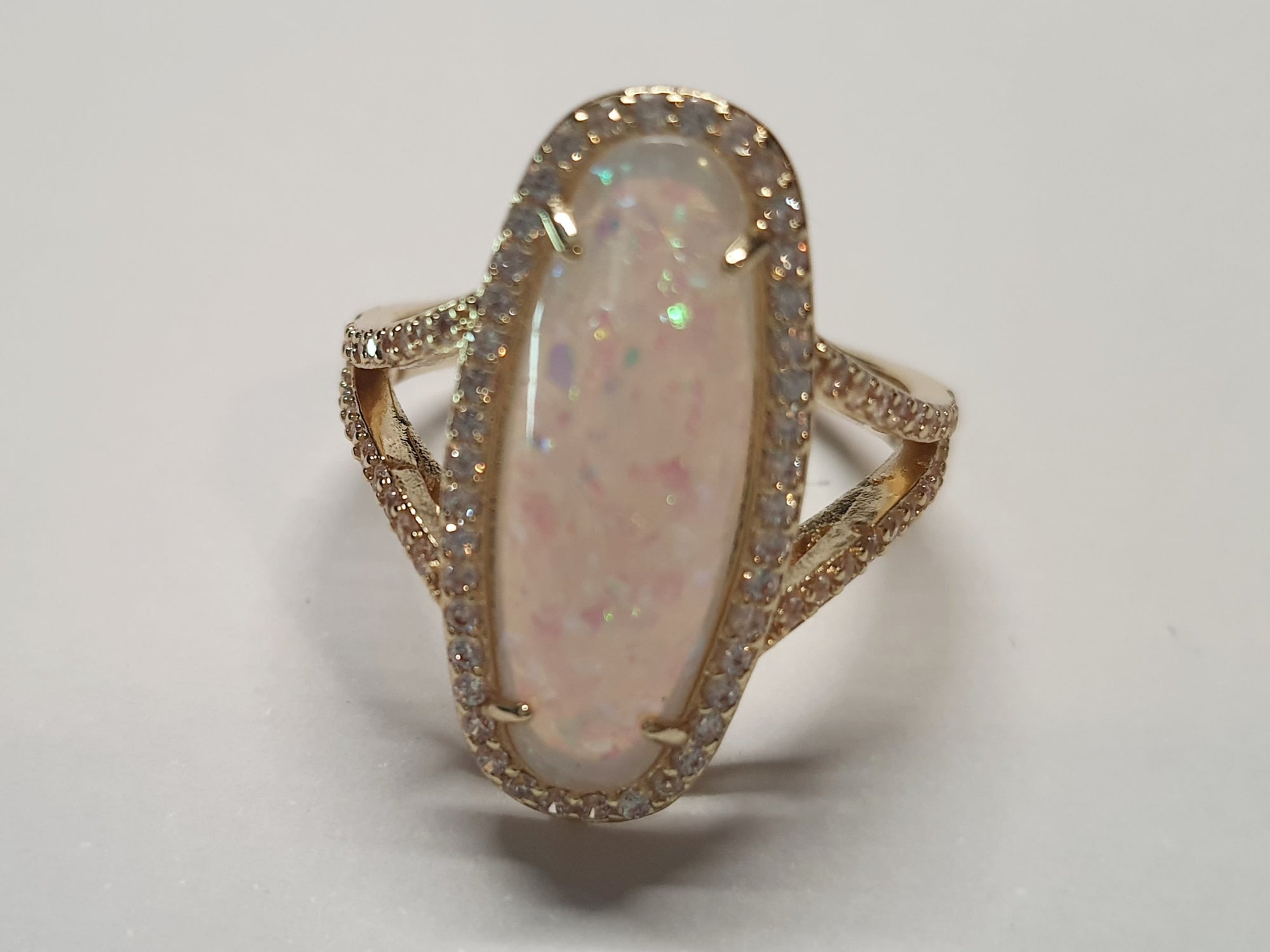 Złoty pierścionek ze stali nierdzewnej z podłużnym opalizującym kamieniem i cyrkoniami w stylu glamour eleganckim. Rozmiar 19 mm. stal chirurgiczna, stal nierdzewna, wodoodporne, hipoalergiczne, jakość premium, RougeBizu.
