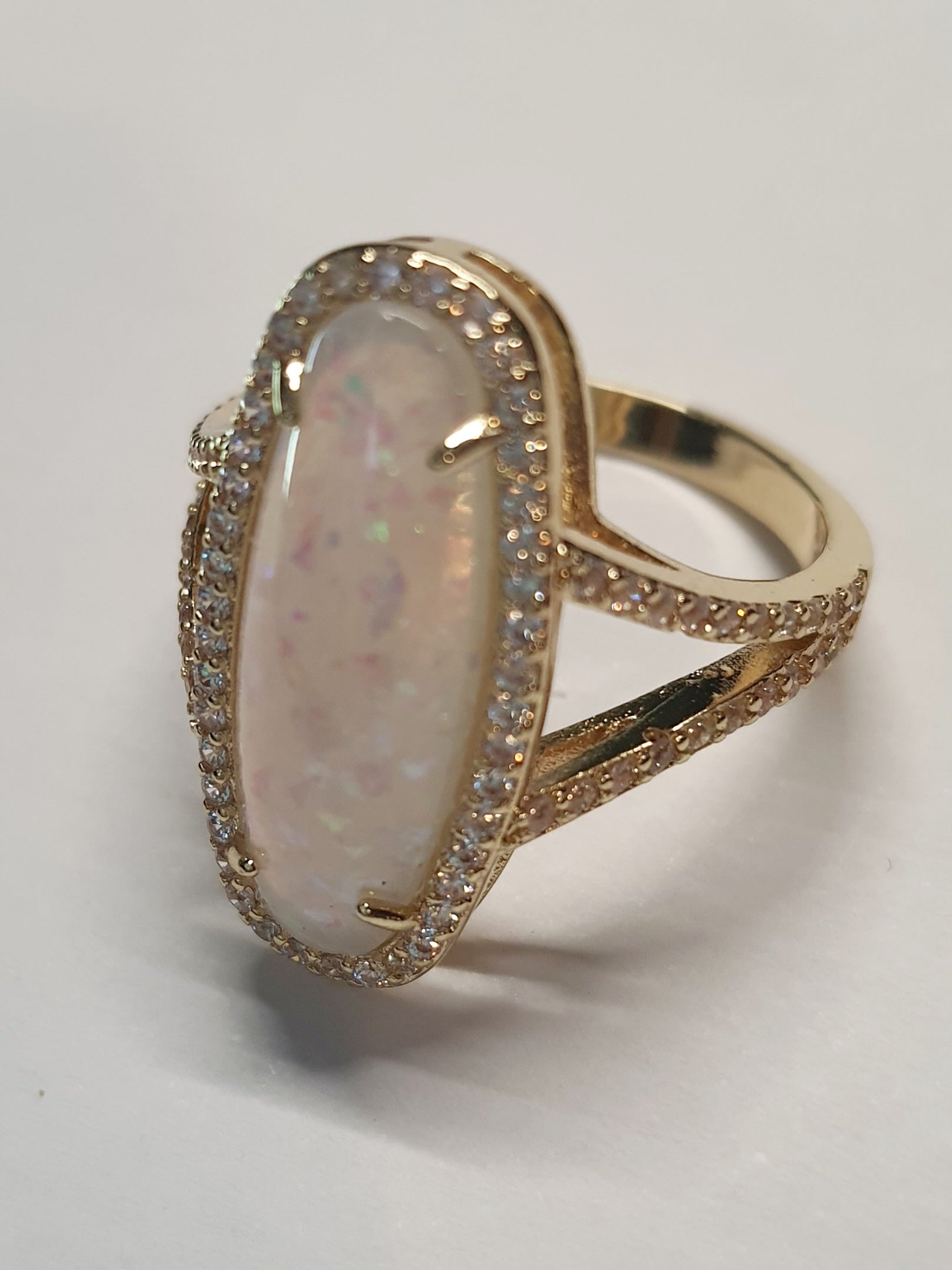 Złoty pierścionek ze stali nierdzewnej z podłużnym opalizującym kamieniem i cyrkoniami w stylu glamour eleganckim. Rozmiar 19 mm. stal chirurgiczna, stal nierdzewna, wodoodporne, hipoalergiczne, jakość premium, RougeBizu.