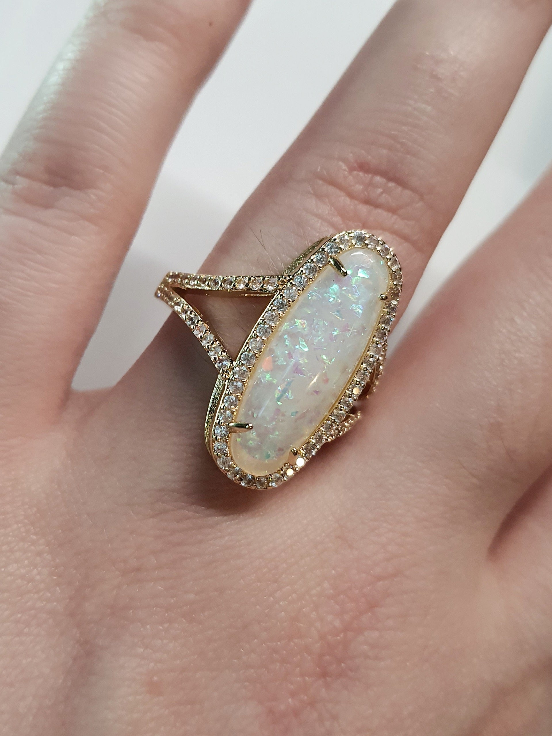 Złoty pierścionek ze stali nierdzewnej z podłużnym opalizującym kamieniem i cyrkoniami w stylu glamour eleganckim. Rozmiar 19 mm. stal chirurgiczna, stal nierdzewna, wodoodporne, hipoalergiczne, jakość premium, RougeBizu.