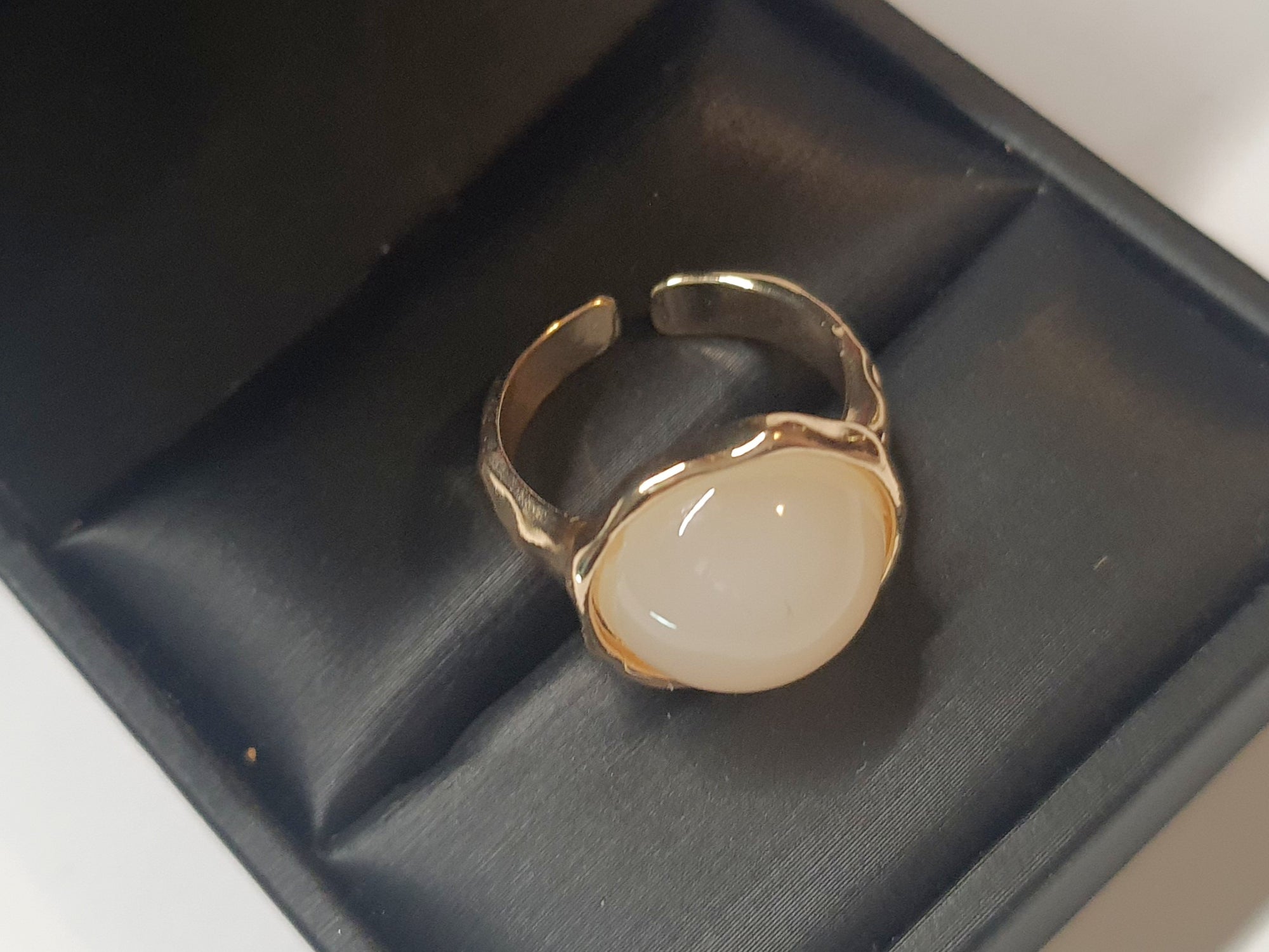 Złoty pierścionek z kremowym kamieniem w falującej oprawie, stal chirurgiczna, stal nierdzewna, polerowany, elegancki, minimalistyczny, rozmiar 15 mm, wodoodporny, hipoalergiczny, jakość premium, Rouge Bizu.