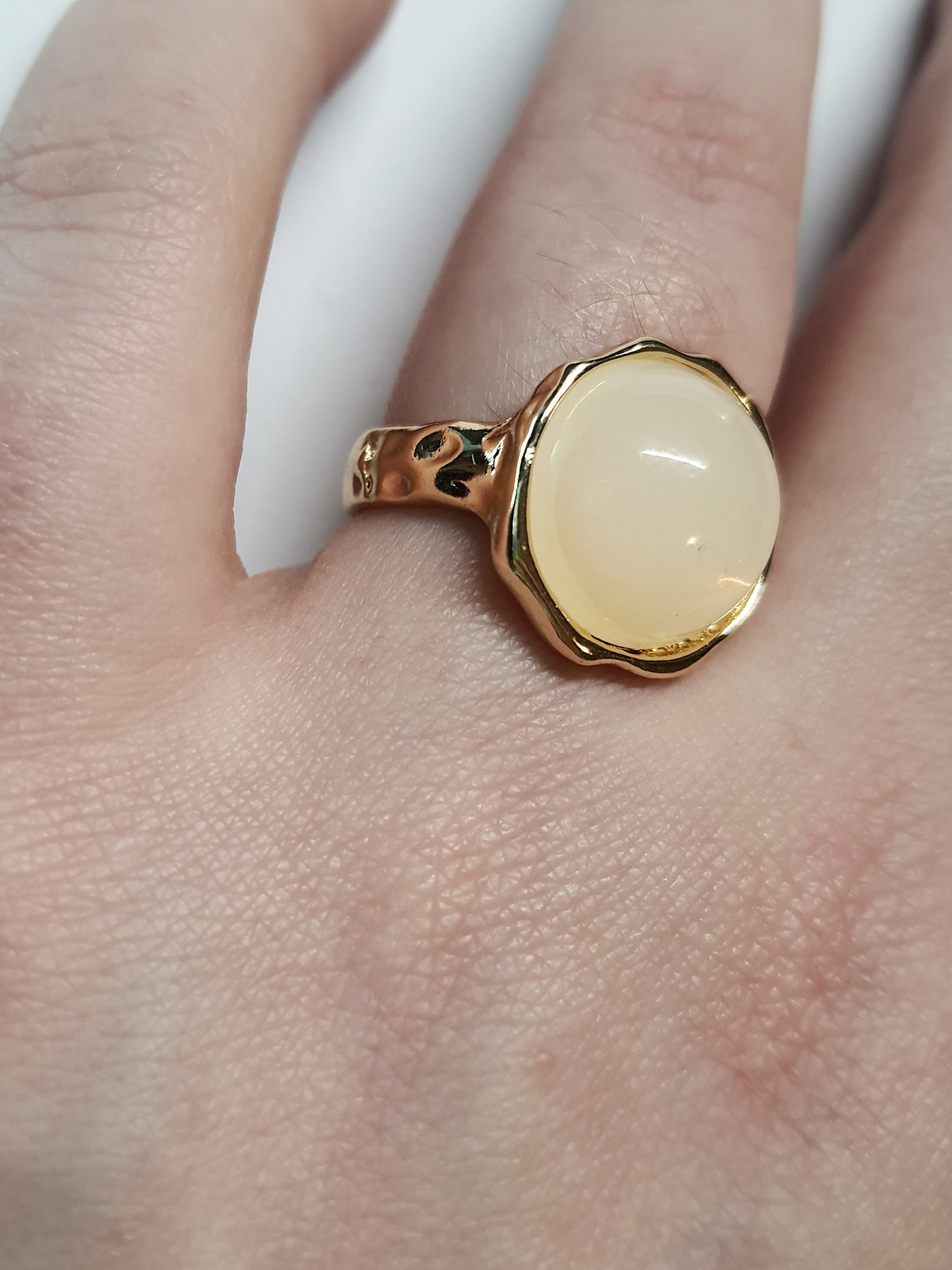 Złoty pierścionek z kremowym kamieniem w falującej oprawie, stal chirurgiczna, stal nierdzewna, polerowany, elegancki, minimalistyczny, rozmiar 15 mm, wodoodporny, hipoalergiczny, jakość premium, Rouge Bizu.