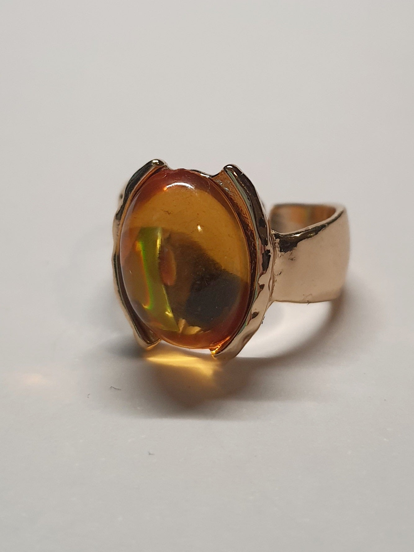 Złoty pierścionek ze stali nierdzewnej z owalnym bursztynowym kamieniem w artystycznej oprawie o nieregularnej formie. Rozmiar 16 mm. stal chirurgiczna, stal nierdzewna, wodoodporne, hipoalergiczne, jakość premium, RougeBizu.