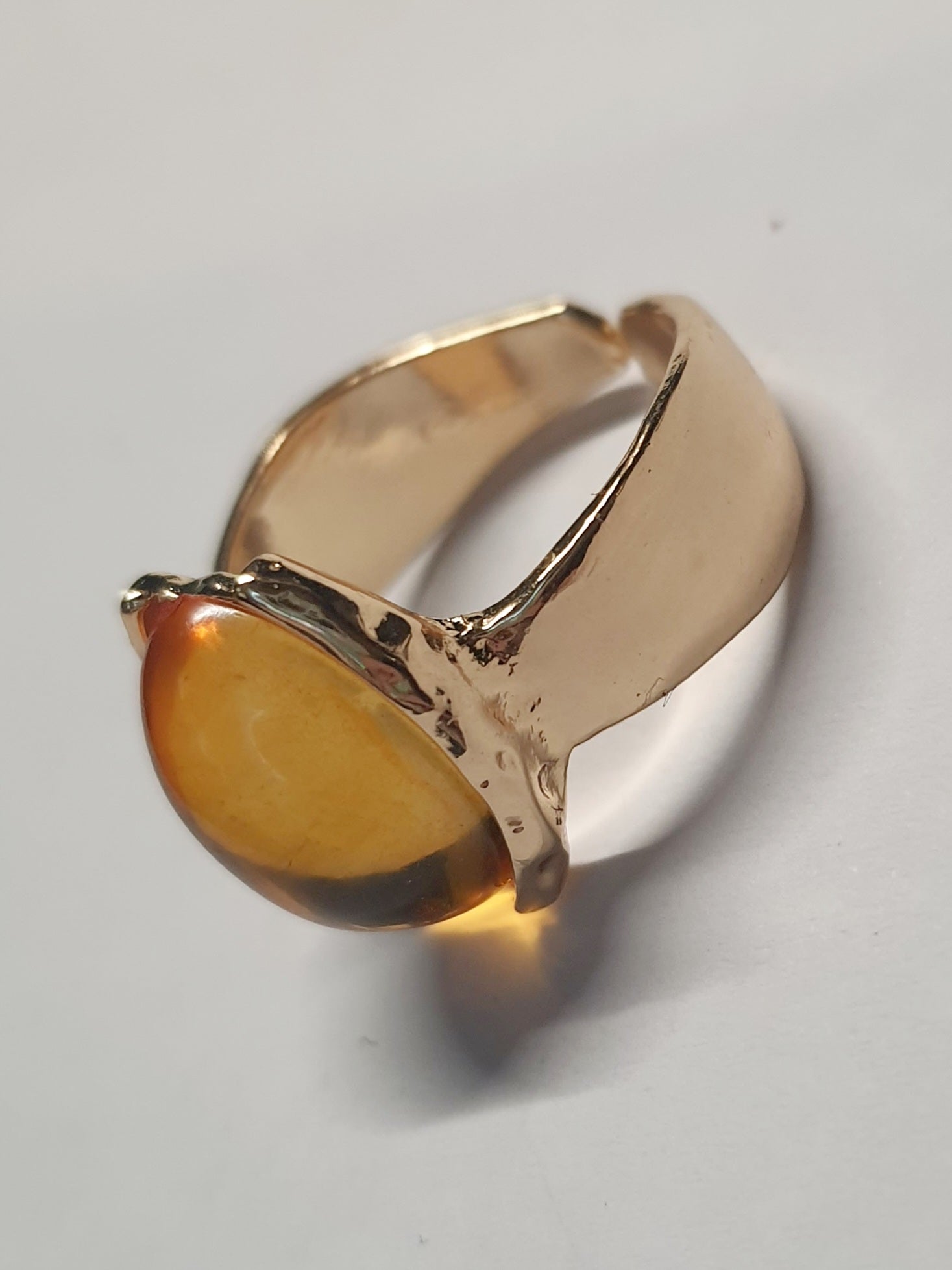 Złoty pierścionek ze stali nierdzewnej z owalnym bursztynowym kamieniem w artystycznej oprawie o nieregularnej formie. Rozmiar 16 mm. stal chirurgiczna, stal nierdzewna, wodoodporne, hipoalergiczne, jakość premium, RougeBizu.