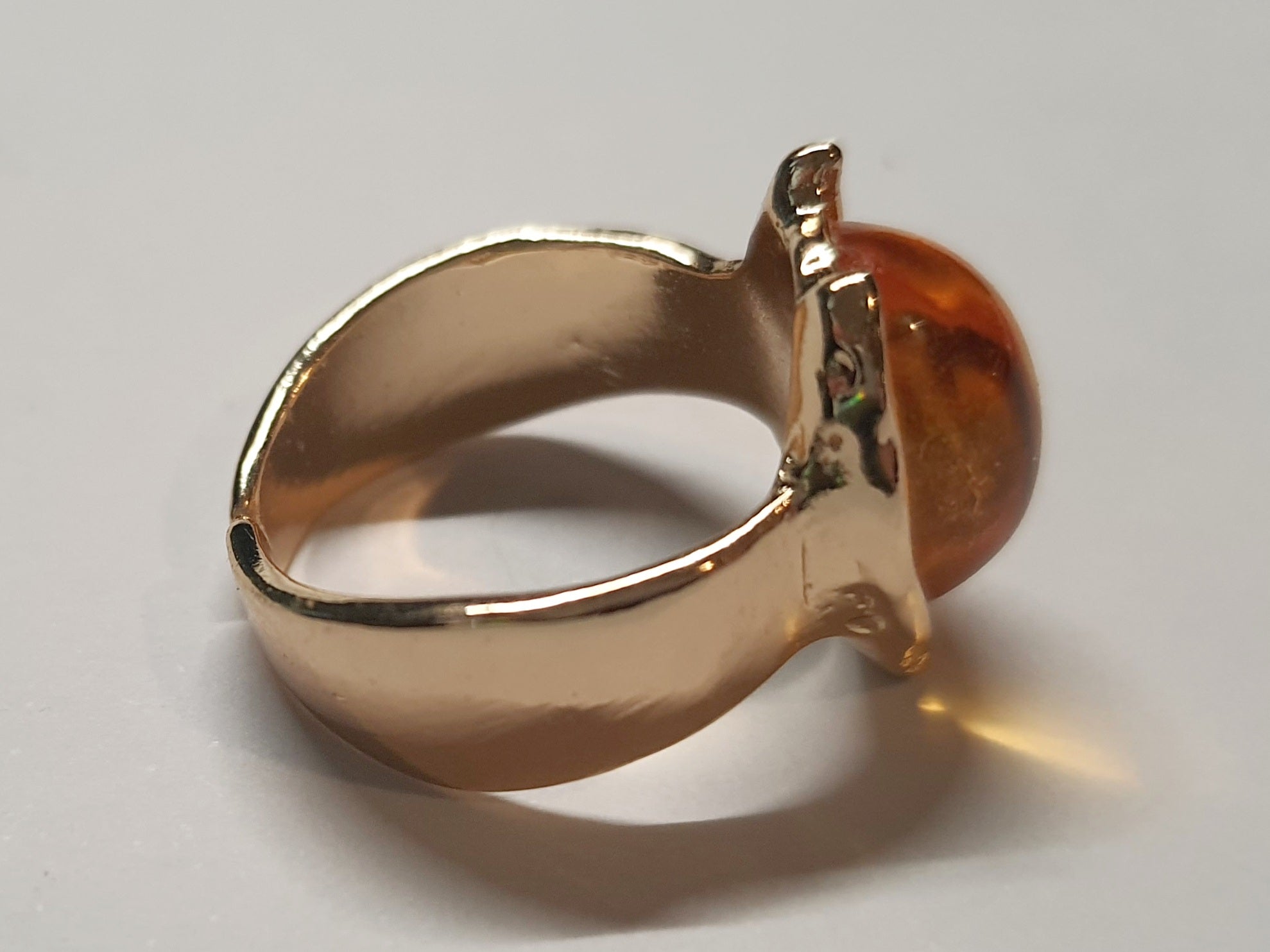 Złoty pierścionek ze stali nierdzewnej z owalnym bursztynowym kamieniem w artystycznej oprawie o nieregularnej formie. Rozmiar 16 mm. stal chirurgiczna, stal nierdzewna, wodoodporne, hipoalergiczne, jakość premium, RougeBizu.