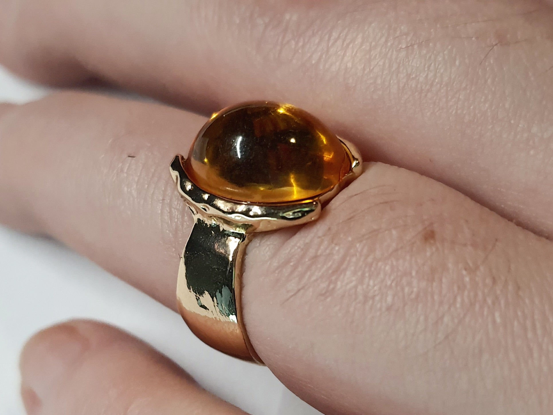 Złoty pierścionek ze stali nierdzewnej z owalnym bursztynowym kamieniem w artystycznej oprawie o nieregularnej formie. Rozmiar 16 mm. stal chirurgiczna, stal nierdzewna, wodoodporne, hipoalergiczne, jakość premium, RougeBizu.