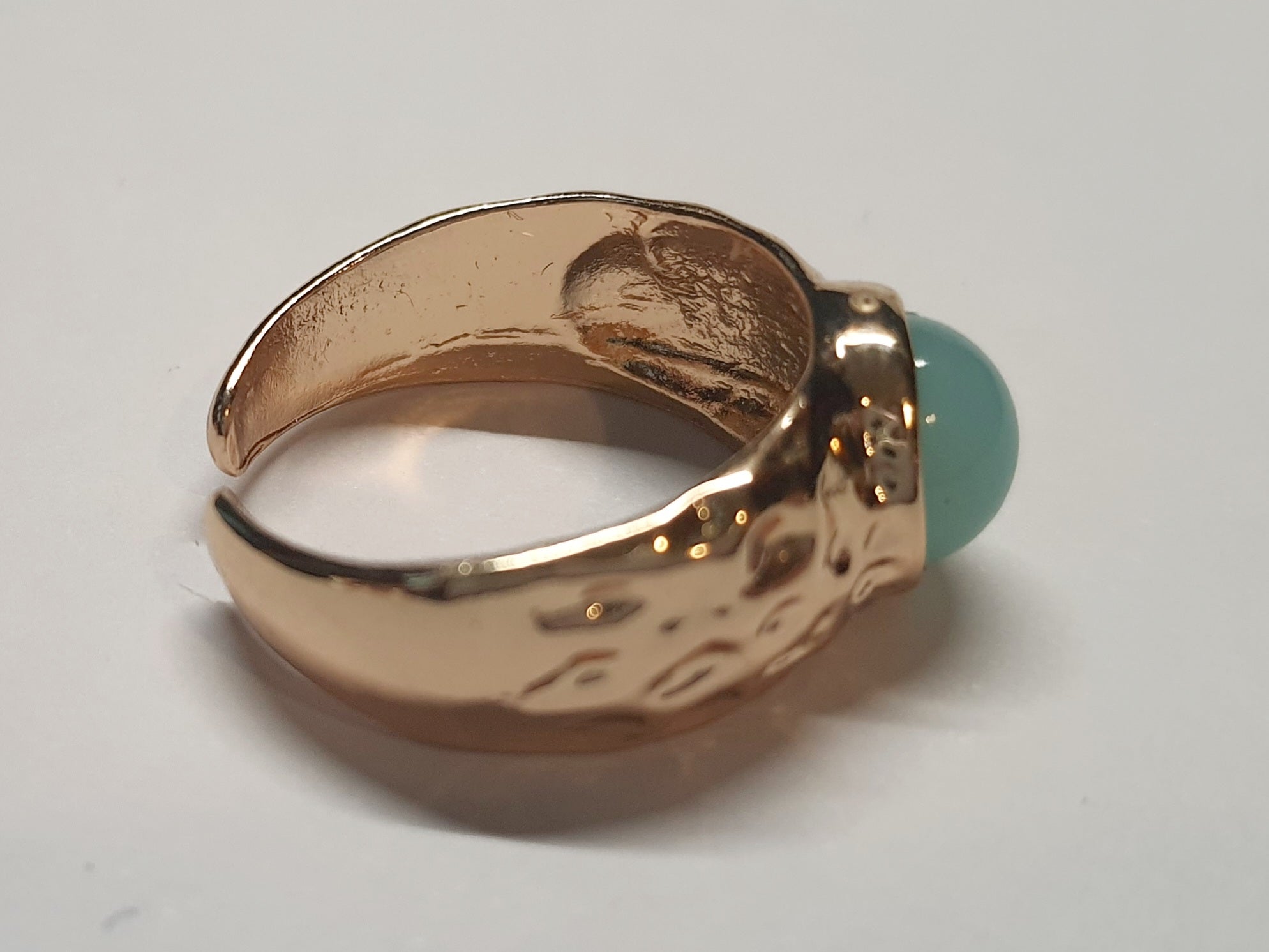 Złoty pierścionek z mleczno–turkusowym kamieniem w młotkowanej oprawie, elegancki i nowoczesny. Rozmiar 17 mm, regulowany. Stal nierdzewna, stal chirurgiczna, wodoodporne, hipoalergiczne, jakość premium. Rouge Bizu.