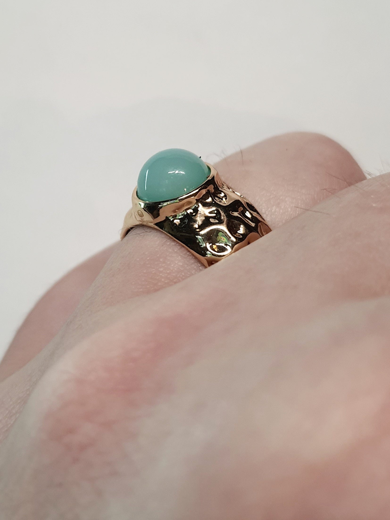 Złoty pierścionek z mleczno–turkusowym kamieniem w młotkowanej oprawie, elegancki i nowoczesny. Rozmiar 17 mm, regulowany. Stal nierdzewna, stal chirurgiczna, wodoodporne, hipoalergiczne, jakość premium. Rouge Bizu.
