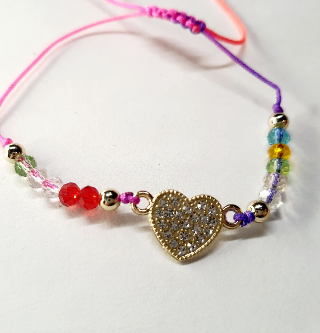 Bransoletka z sercem wysadzanym cyrkoniami na różowo-fioletowym sznurku z kolorowymi koralikami. Delikatna, kolorowa biżuteria w stylu boho, romantyczna i radosna. Wodoodporne, hipoalergiczne, jakość premium. Rouge Bizu.