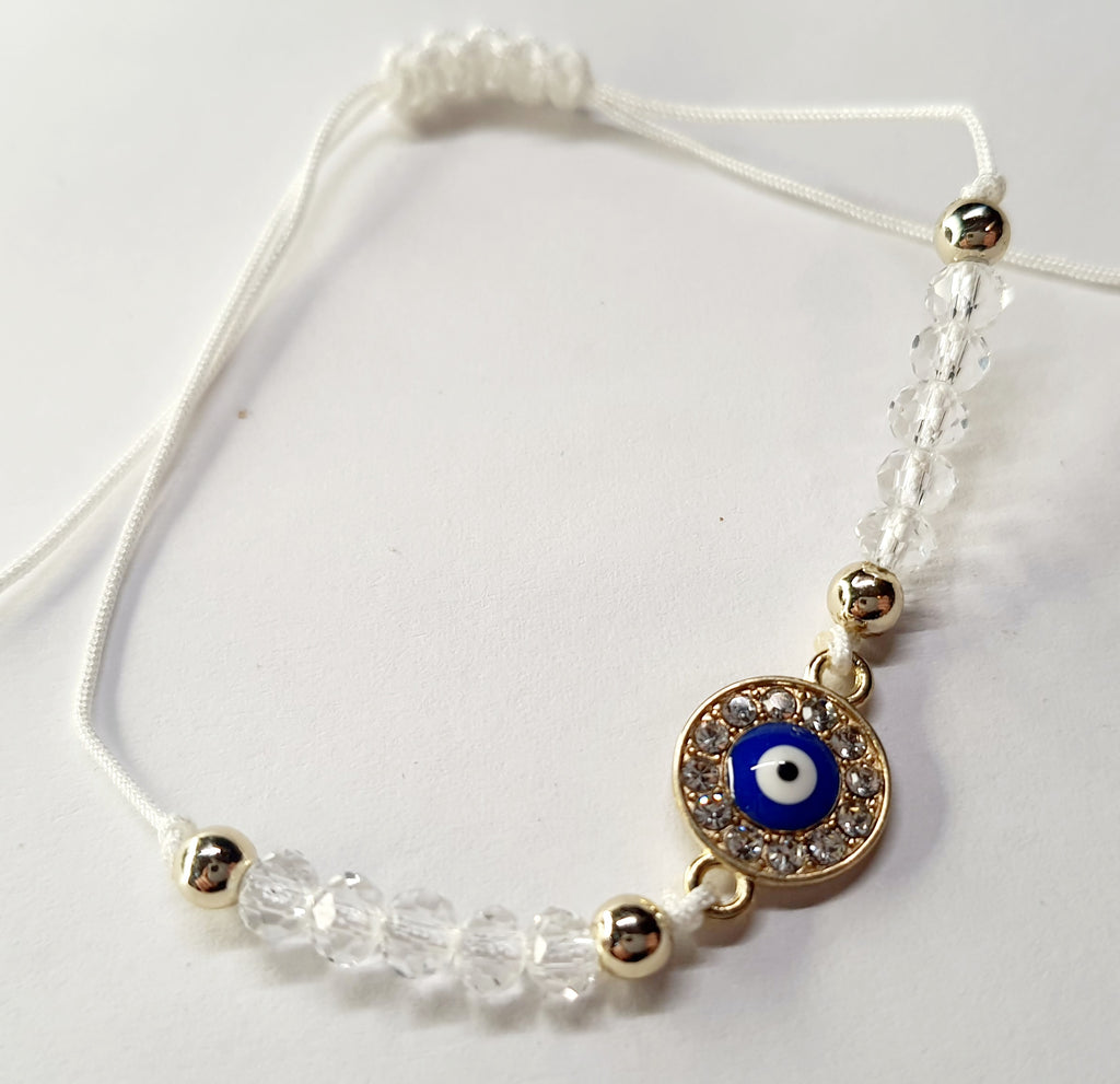 Biała bransoletka na sznurku z niebieskim okiem proroka w złotej oprawie wysadzanej cyrkoniami, z przezroczystymi koralikami. Delikatna, ochronna biżuteria w stylu boho. Wodoodporne, hipoalergiczne, jakość premium. Rouge Bizu.