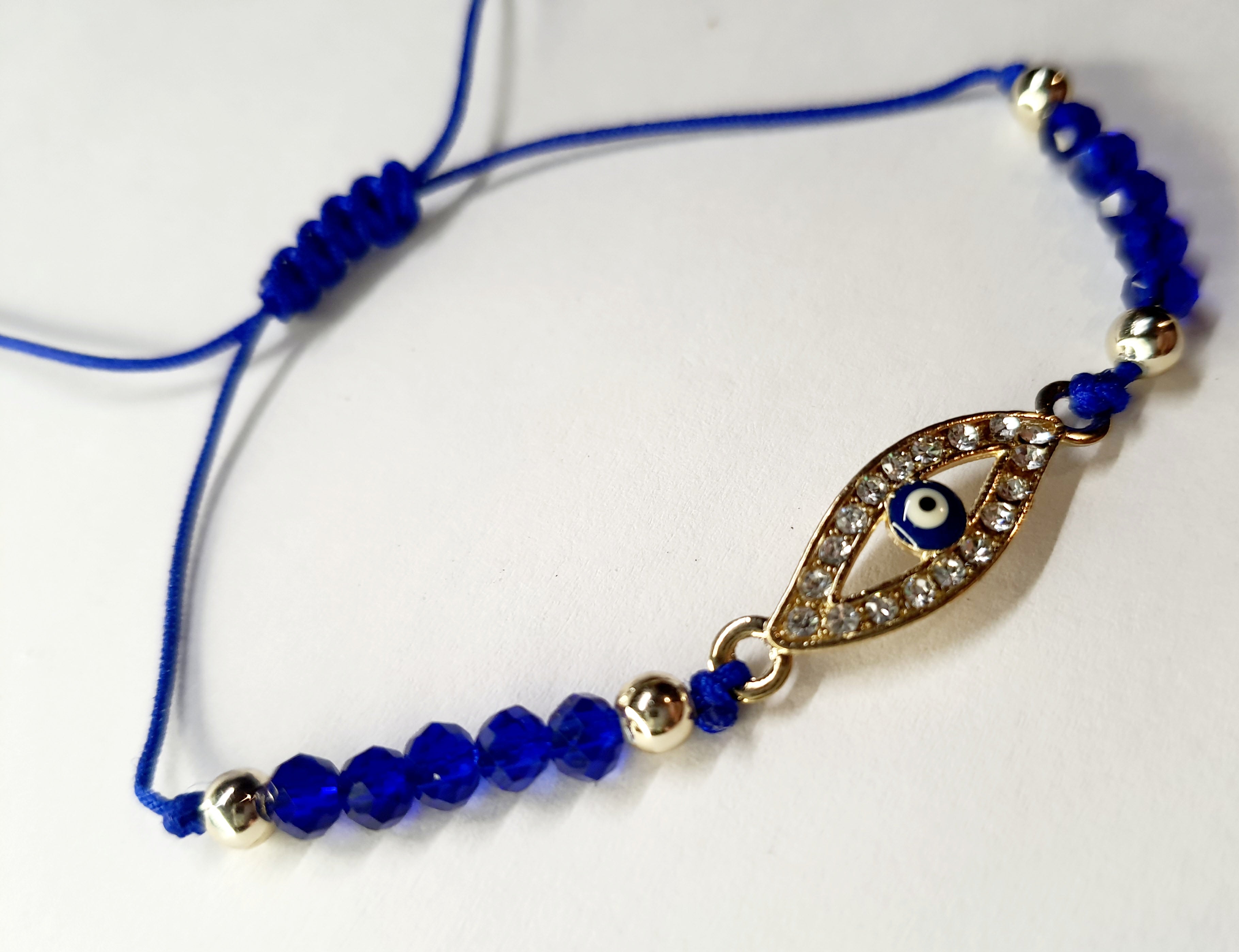 Bransoletka z okiem proroka w złotej oprawie wysadzanej cyrkoniami, na granatowym sznurku z ciemnoniebieskimi koralikami. Elegancka, ochronna biżuteria w stylu boho. Wodoodporne, hipoalergiczne, jakość premium. Rouge Bizu.