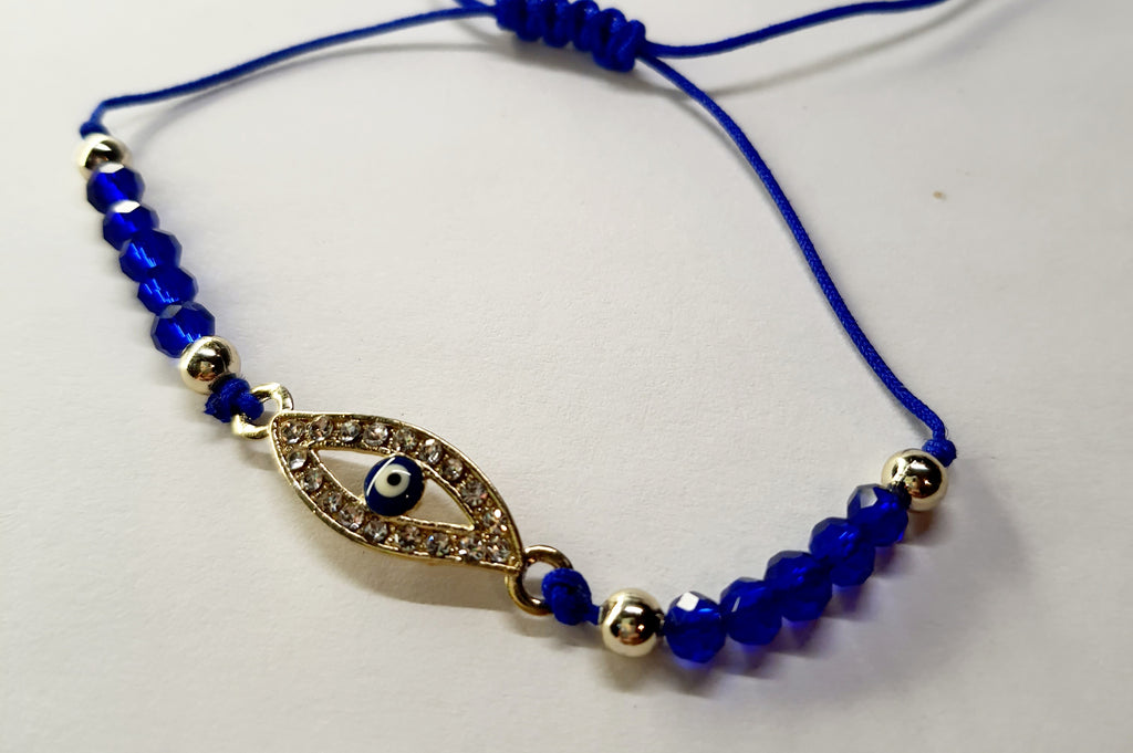 Bransoletka z okiem proroka w złotej oprawie wysadzanej cyrkoniami, na granatowym sznurku z ciemnoniebieskimi koralikami. Elegancka, ochronna biżuteria w stylu boho. Wodoodporne, hipoalergiczne, jakość premium. Rouge Bizu.