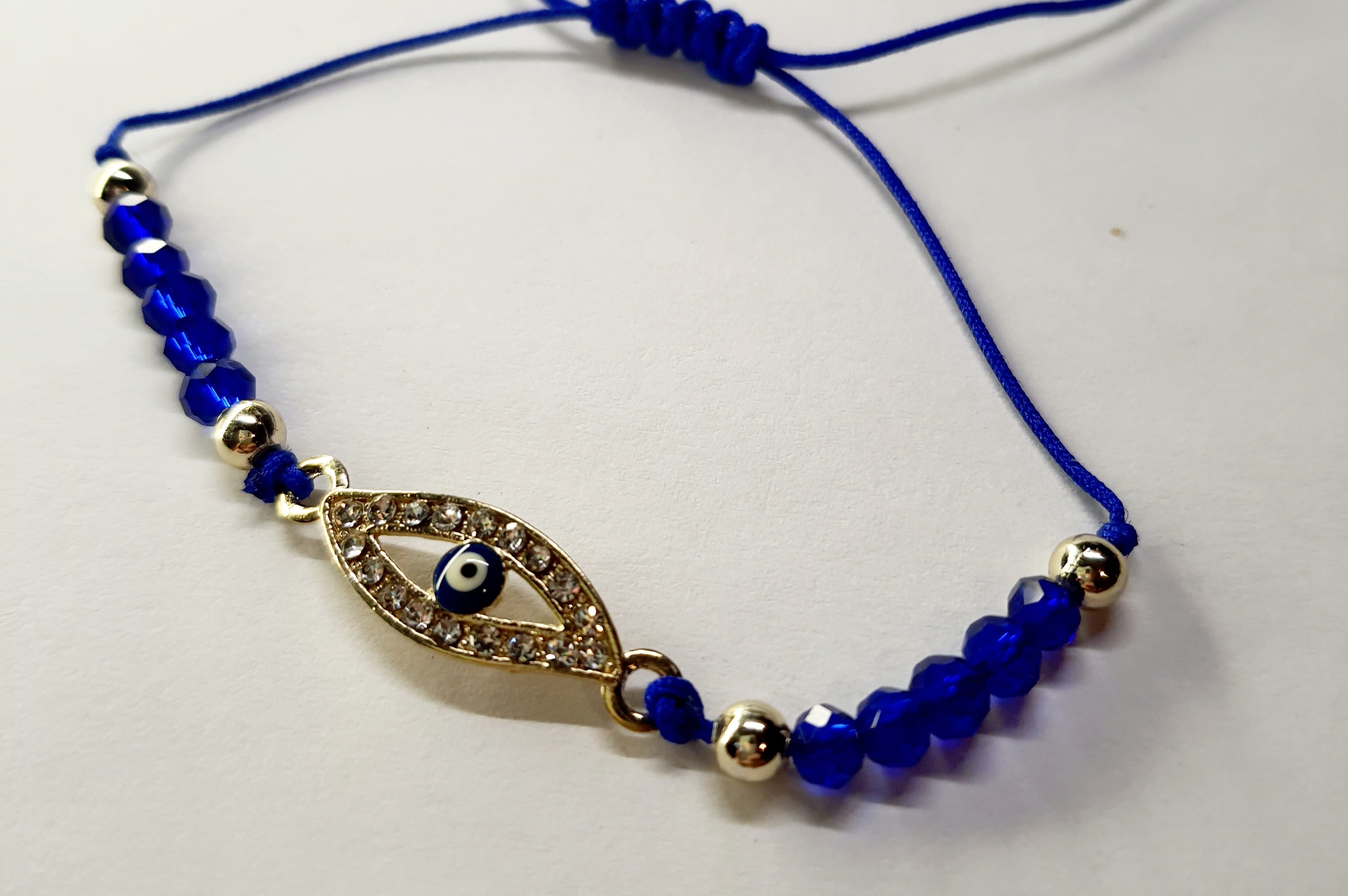 Bransoletka z okiem proroka w złotej oprawie wysadzanej cyrkoniami, na granatowym sznurku z ciemnoniebieskimi koralikami. Elegancka, ochronna biżuteria w stylu boho. Wodoodporne, hipoalergiczne, jakość premium. Rouge Bizu.