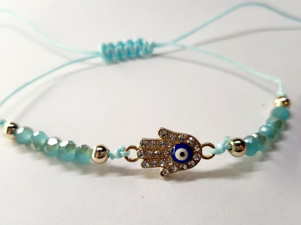 Bransoletka z dłonią Fatimy (Hamsa) wysadzaną cyrkoniami i okiem proroka, na miętowym sznurku z miętowymi koralikami. Delikatna, ochronna biżuteria w stylu boho. Wodoodporne, hipoalergiczne, jakość premium. Rouge Bizu.