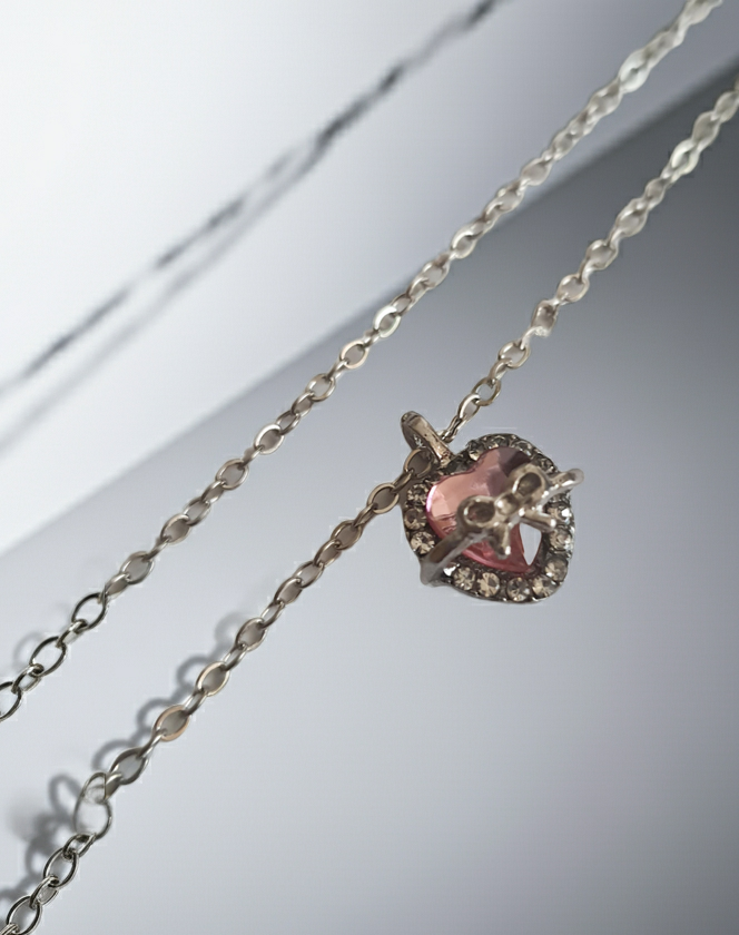 Srebrny naszyjnik ze stali nierdzewnej – stal chirurgiczna, wodoodporny, hipoalergiczny, jakość premium. Zawieszka w kształcie różowego serca z kokardką i otoczką z cyrkonii. Długość łańcuszka 42–49 cm. RougeBizu.