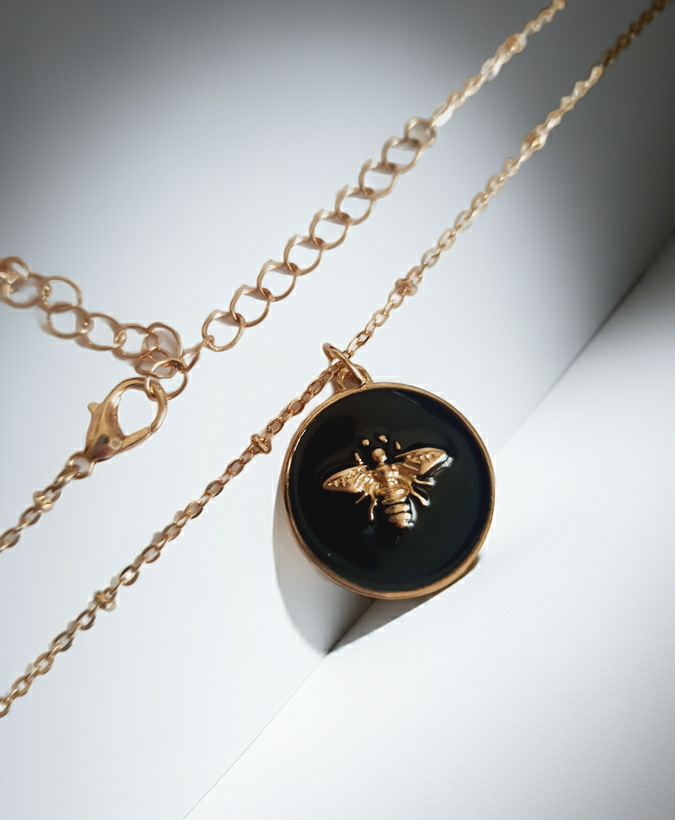 Złoty naszyjnik ze stali chirurgicznej z czarną okrągłą zawieszką i złotą pszczółką. Regulowana długość 40–49 cm. Stal chirurgiczna, stal nierdzewna, wodoodporne, hipoalergiczne, jakość premium. RougeBizu.