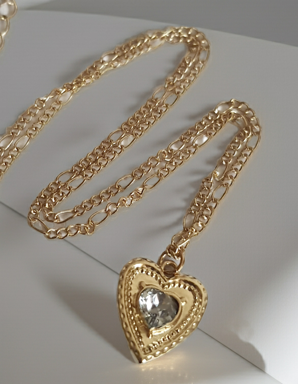 Złoty naszyjnik ze stali chirurgicznej, łańcuszek 43–50 cm, zawieszka w kształcie serca z centralnym kryształem, elegancja i romantyczny styl. Stal nierdzewna, wodoodporne, hipoalergiczne, jakość premium. Rouge Bizu.