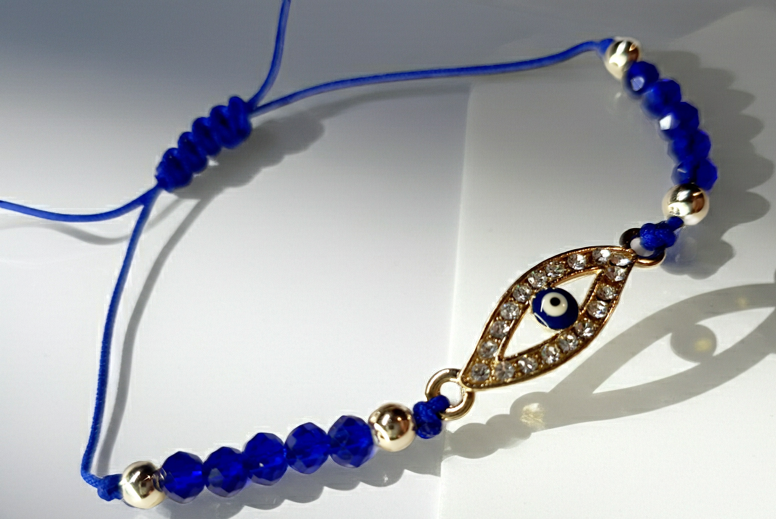 Bransoletka z okiem proroka w złotej oprawie wysadzanej cyrkoniami, na granatowym sznurku z ciemnoniebieskimi koralikami. Elegancka, ochronna biżuteria w stylu boho. Wodoodporne, hipoalergiczne, jakość premium. Rouge Bizu.
