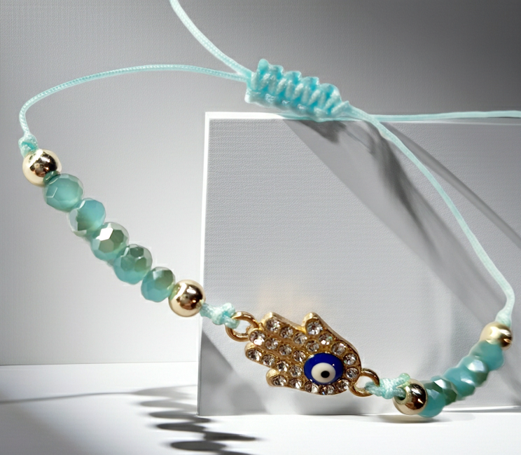 Bransoletka z dłonią Fatimy (Hamsa) wysadzaną cyrkoniami i okiem proroka, na miętowym sznurku z miętowymi koralikami. Delikatna, ochronna biżuteria w stylu boho. Wodoodporne, hipoalergiczne, jakość premium. Rouge Bizu.