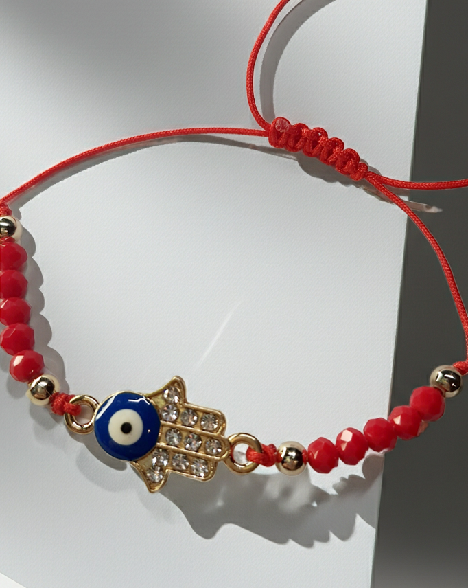Bransoletka na czerwonym sznurku z zawieszką w kształcie dłoni Fatimy z okiem proroka, zdobioną cyrkoniami. Styl boho i amulet ochronny. Stal chirurgiczna, stal nierdzewna, wodoodporne, hipoalergiczne, jakość premium. Rouge Bizu.