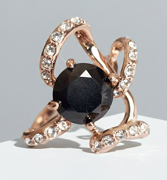 Pierścionek ze złota różowego z dużym czarnym kamieniem w centrum i zdobieniami z drobnych cyrkonii. Styl glamour, rozmiar 18 mm. Elegancki, efektowny, wykonany ze stali chirurgicznej. Rouge Bizu.
