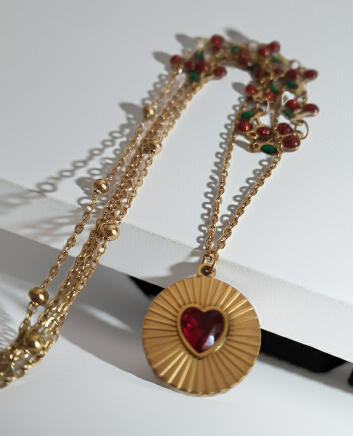 Podwójny złoty naszyjnik ze stali nierdzewnej – stal chirurgiczna, wodoodporny, hipoalergiczny, jakość premium. Pierwsza warstwa z czerwonymi wiśniami i zielonymi listkami, druga z medalionem i czerwonym sercem. Długość 40–50 cm. RougeBizu.
