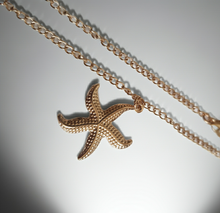 Naszyjnik złoty ze stali nierdzewnej – stal chirurgiczna, wodoodporny, hipoalergiczny, jakość premium. Zawieszka w kształcie złotej rozgwiazdy o fakturowanej powierzchni. Długość łańcuszka 47–53 cm. Styl RougeBizu.