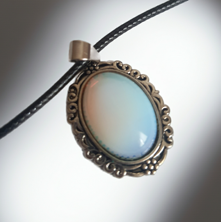Naszyjnik vintage ze stali nierdzewnej – stal chirurgiczna, wodoodporny, hipoalergiczny, jakość premium. Zawieszka owalna z syntetycznym opalem opalizującym błękitem i bielą, w zdobionej ramie. Czarna linka o długości 45–50 cm. Styl RougeBizu.