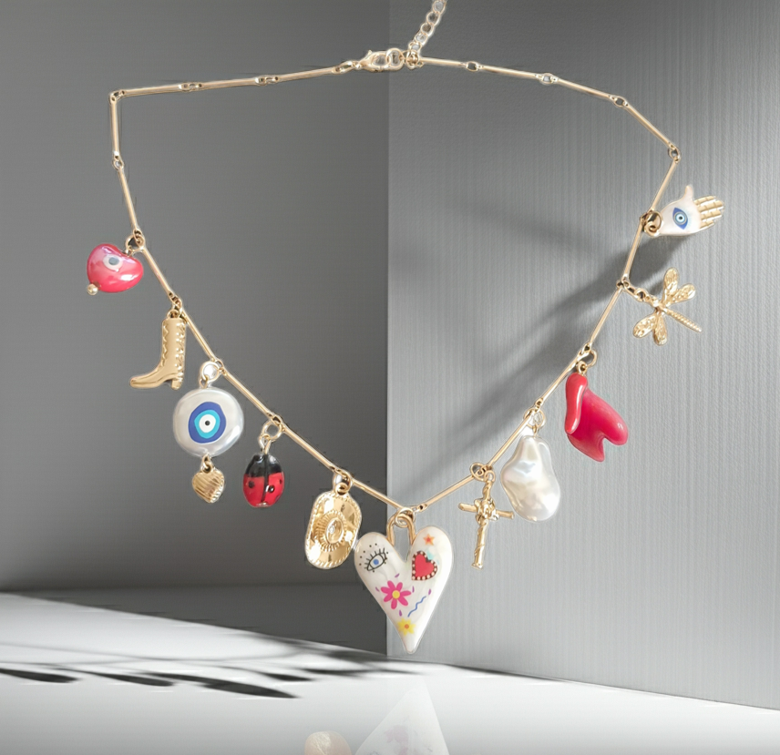 Złoty naszyjnik ze stali chirurgicznej z charmsami – sercem, biedronką, perłą syntetyczną, krzyżykiem, okiem proroczym, dłonią Fatimy, ważką i innymi symbolami. Regulowana długość 45–50 cm. Stal chirurgiczna, stal nierdzewna, wodoodporne, hipoalergiczne, jakość premium. RougeBizu.