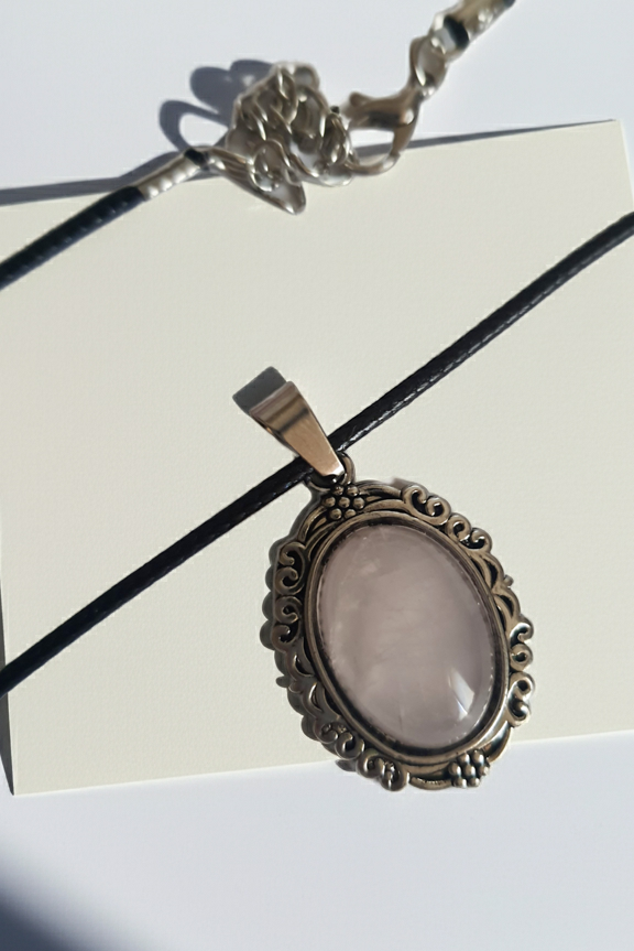 Naszyjnik vintage ze stali chirurgicznej z syntetycznym różowym kwarcem w ozdobnej srebrzystej ramce. Czarny rzemyk, długość regulowana 45–50 cm. Stal chirurgiczna, stal nierdzewna, wodoodporne, hipoalergiczne, jakość premium. RougeBizu.