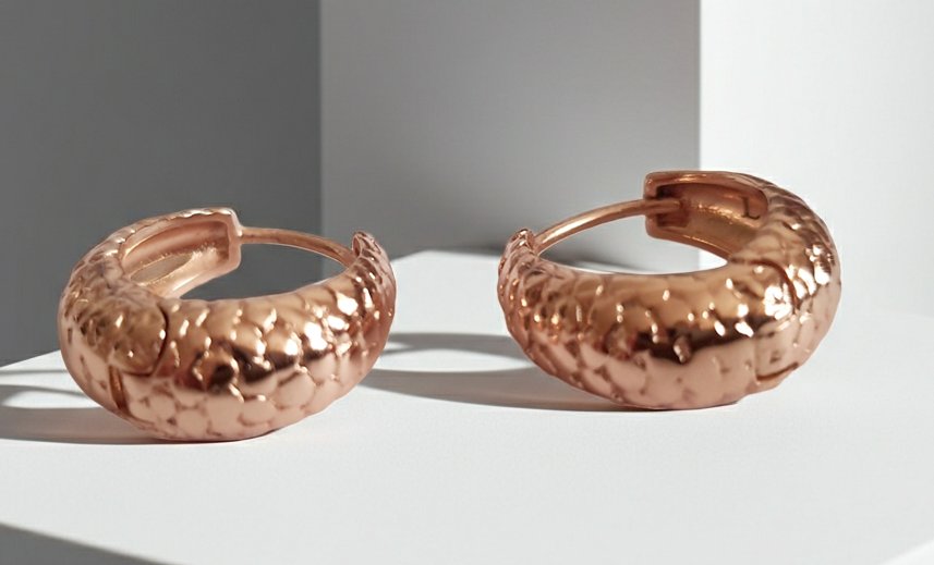 Kolczyki huggie ze stali chirurgicznej w kolorze różowego złota, z młotkowaną fakturą, średnica 1,2 cm. Klasyczny styl z fakturowanym wykończeniem. Rouge Bizu.
