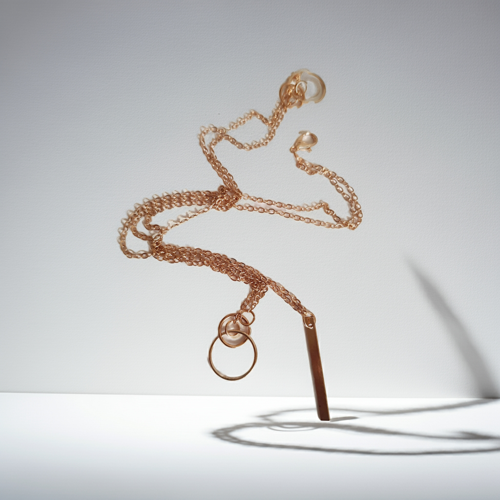 Przewlekany łańcuszek celebrytka ze stali chirurgicznej w kolorze żółtego złota, z dwiema obręczami i prostą podłużną zawieszką. Długość maksymalna 55 cm. Minimalistyczny styl. Rouge Bizu.

