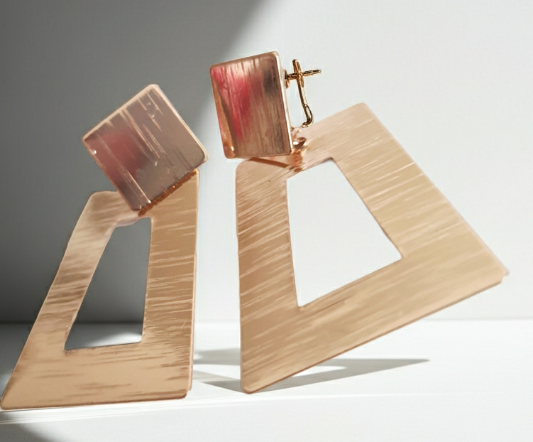 Geometryczne kolczyki z różowego złota o długości 5 cm, wykonane ze stali nierdzewnej. Trapez z wycięciem i kwadratowa baza w formie wkrętki. Nowoczesny, minimalistyczny design w stylu art deco. Rouge Bizu.
