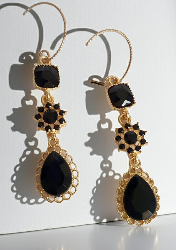 Kolczyki długie ze stali nierdzewnej w kolorze złota z czarnymi kamieniami. Zdobienia w formie kwadratu, rozetki i kropli. Długość 5 cm bez bigla, 6,5 cm z biglem. Styl glamour i elegancki. Rouge Bizu.