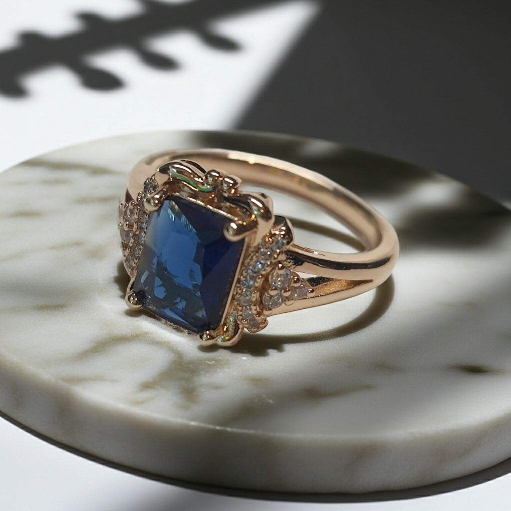 Złoty pierścionek ze stali nierdzewnej z granatowym kamieniem w szlifie szmaragdowym i cyrkoniami po bokach w stylu glamour klasycznym. Rozmiar 20 mm. stal chirurgiczna, stal nierdzewna, wodoodporne, hipoalergiczne, jakość premium, RougeBizu.