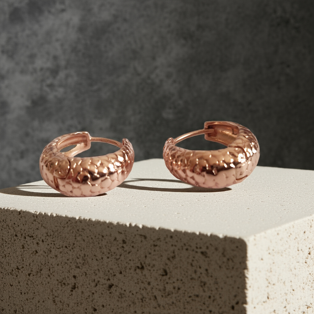 Kolczyki huggie ze stali chirurgicznej w kolorze różowego złota, z młotkowaną fakturą, średnica 1,2 cm. Klasyczny styl z fakturowanym wykończeniem. Rouge Bizu.

