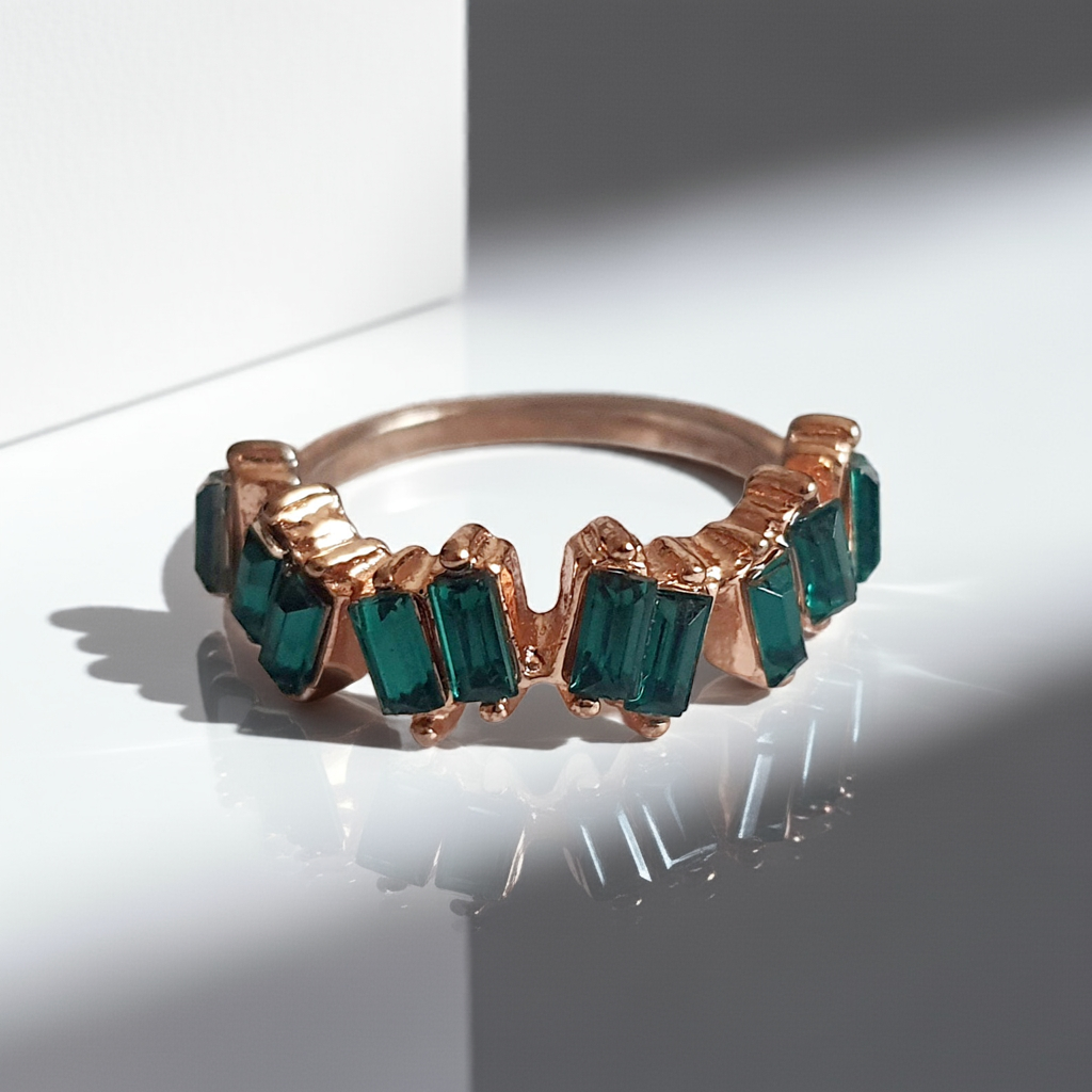 Pierścionek ze stali chirurgicznej w kolorze żółtego złota, ozdobiony szmaragdowymi kryształami typu baguette w górnej części obrączki. Styl minimalistyczny glamour. Rozmiar 18 mm. Rouge Bizu.
