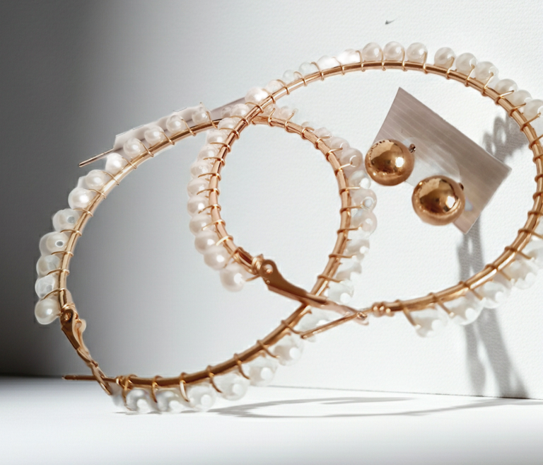 eleganckie kolczyki typu hoops o średnicy 6 cm, oplecione drobnymi perłami, obok złotych wkrętek. stal nierdzewna. rouge bizu
